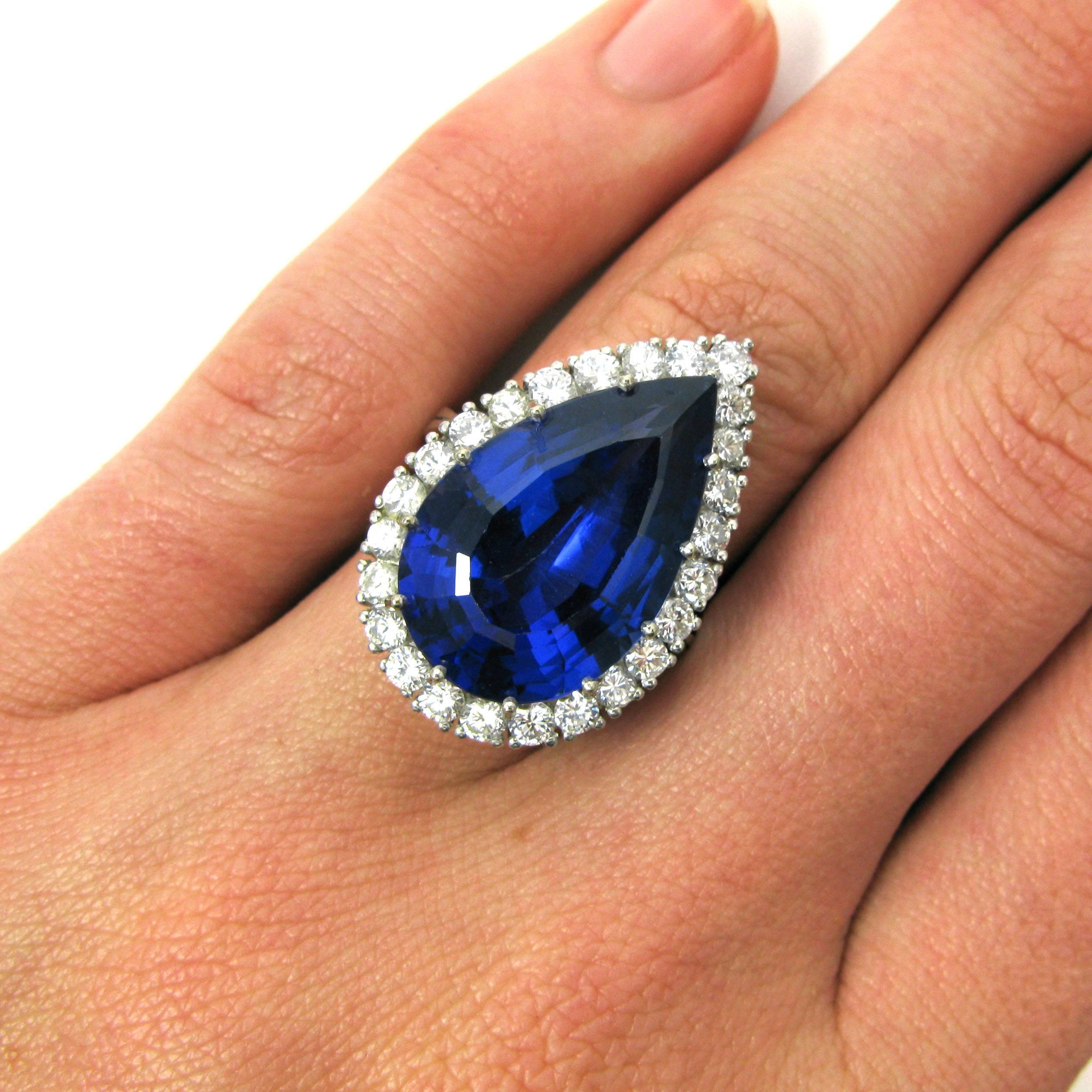 A lovely 13.75 carat pear shaped tanzanite is set into a ballerina-style cocktail ring surrounded by 25 round brilliant-cut diamonds atop a reverse-tapered double ring shank. The tanzanite has a deep, gemmy violet hue while the diamonds weigh