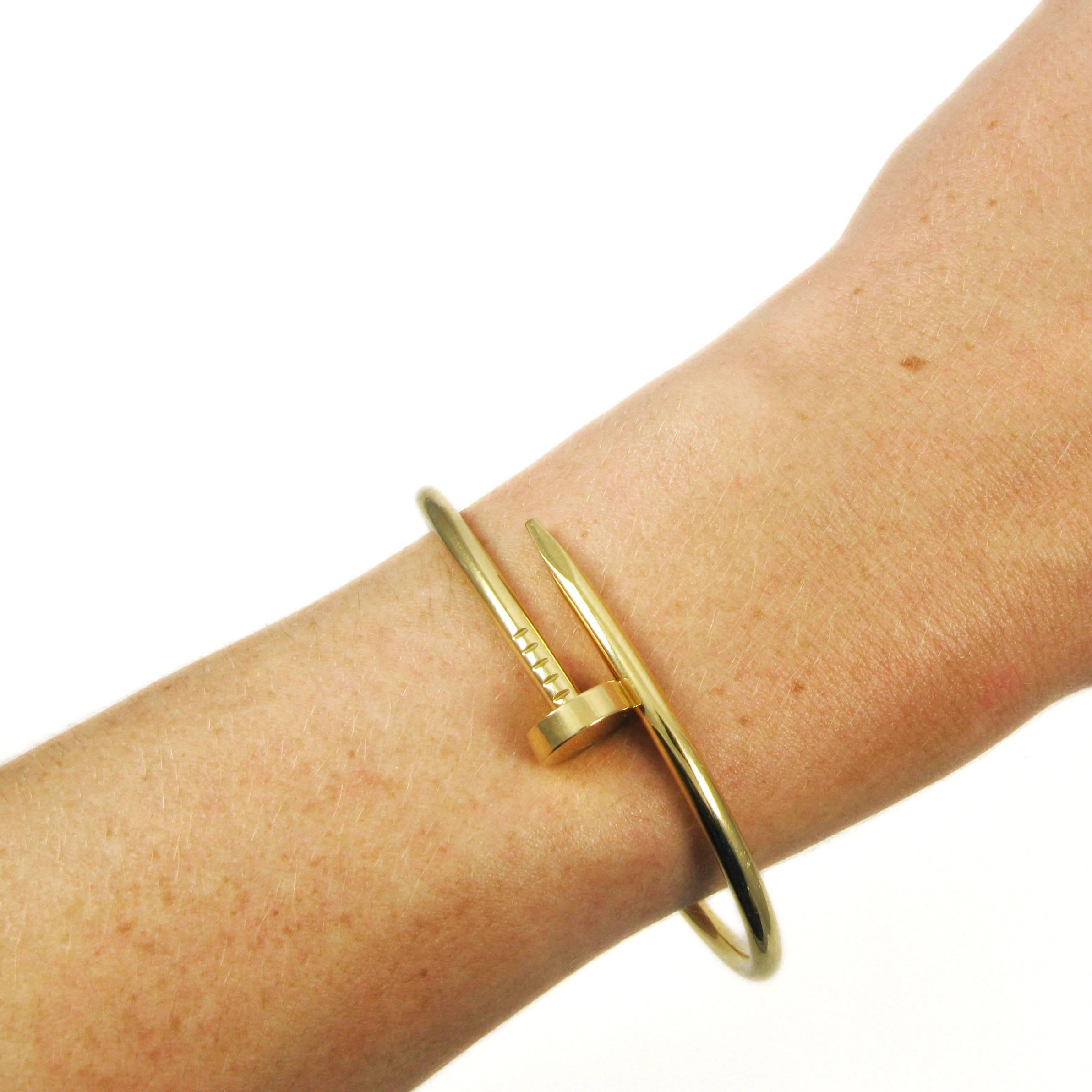 An estate 18k yellow gold "Juste un Clou" bangle bracelet by Cartier. Designed as a curving nail, numbered WI 4236, signed Cartier. Hinged tension closure. Size 18.