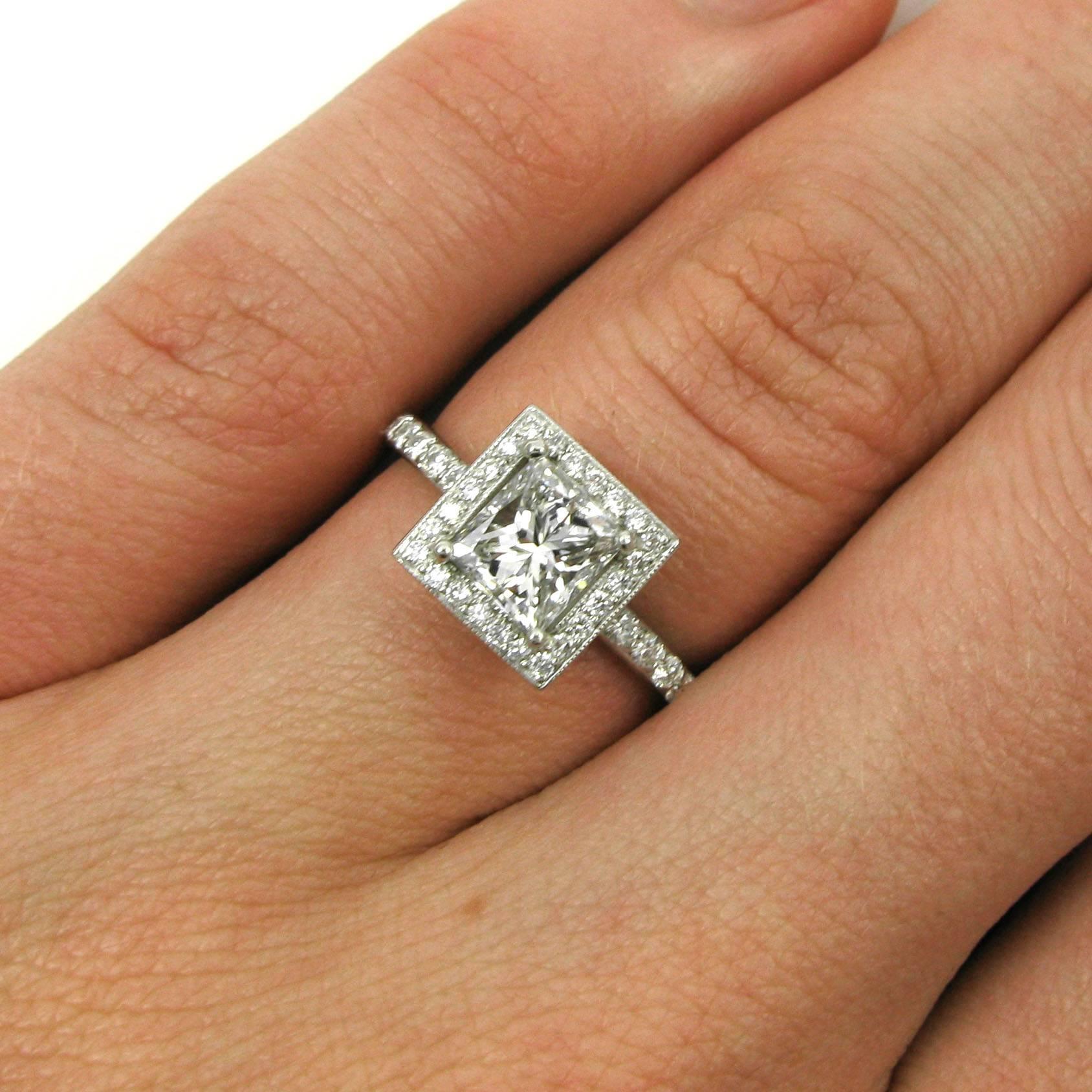A lovely 0.90 princess-cut diamond with E color and VS1 clarity is set into a handmade platinum frame ring with pave shoulders and halo and a lovely filigree boxed gallery. 

Purchase includes GIA Diamond Grading Report 2131246038, which states that