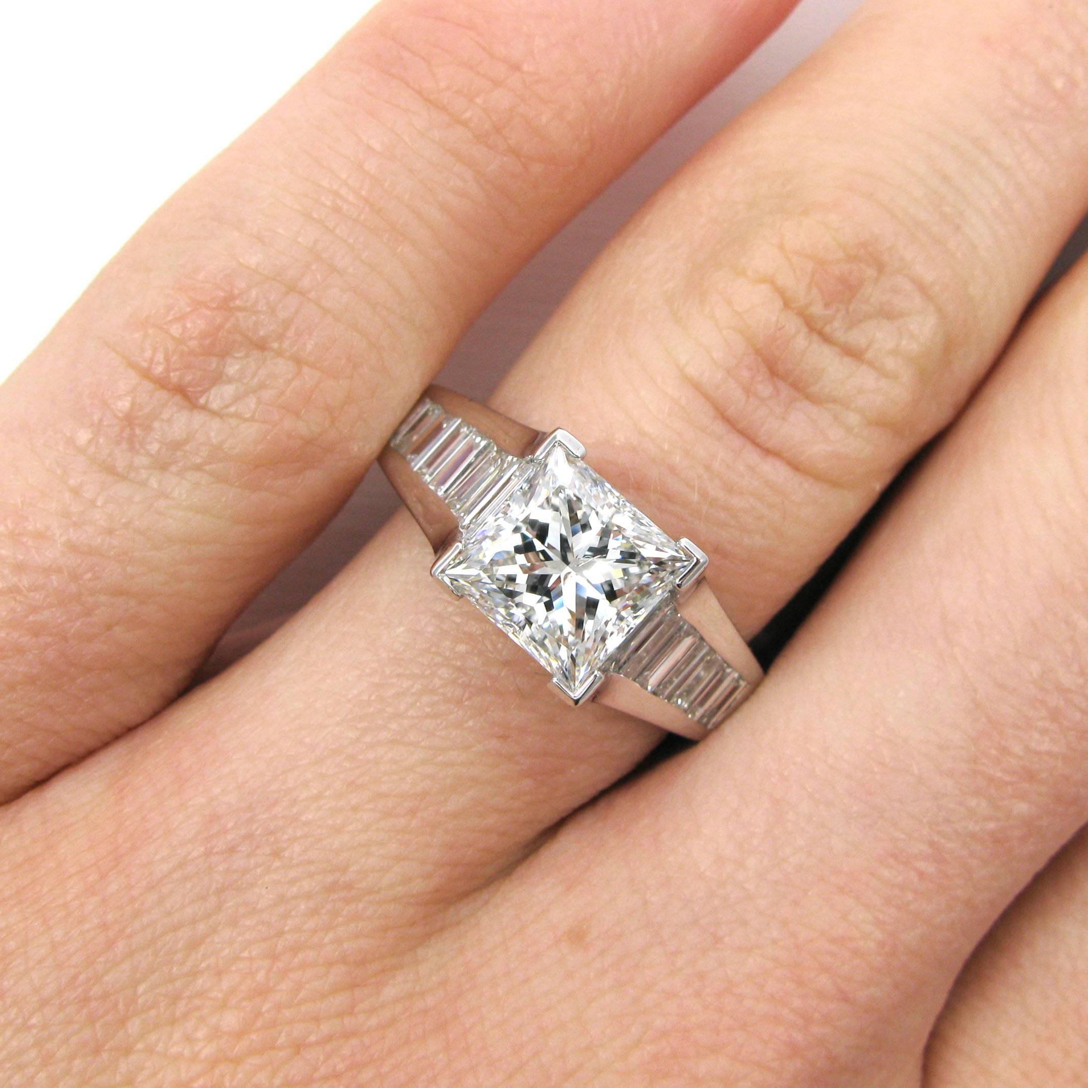 A contemporary ring features a 2.21 carat princess-cut diamond with F color and SI1 clarity. This diamond is set into a heavy 18k white gold mounting with a euro shank and approx. 0.64 carat of straight baguette-cut diamonds channel set down the