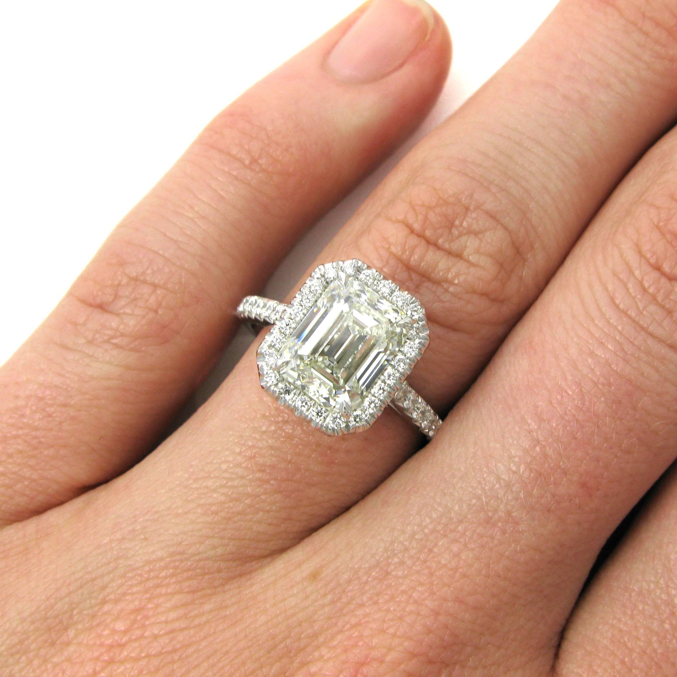 A sleek 3.01 carat emerald cut diamond with G color and VS2 clarity is set in a platinum halo frame ring studded with approx. 0.45 carat total of pave round rounds. 

Purchase includes GIA Diamond Grading Report 2155193152, which states that the