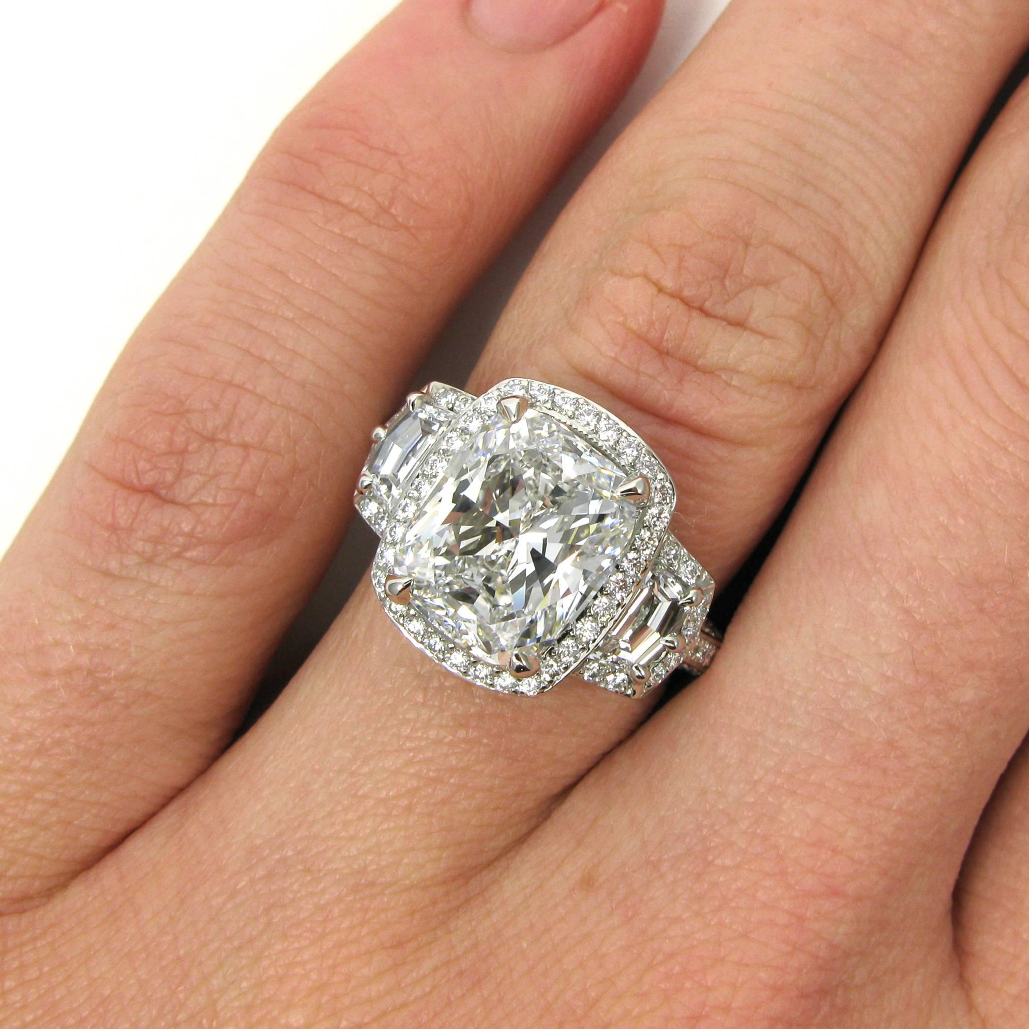 A beautiful 5.00 carat cushion cut diamond with E color and VS1 clarity is set into an impressive platinum three stone frame mounting. The cushion is flanked by two epaulet-cut diamonds totaling 0.44 carat while the entire ring is studded with round