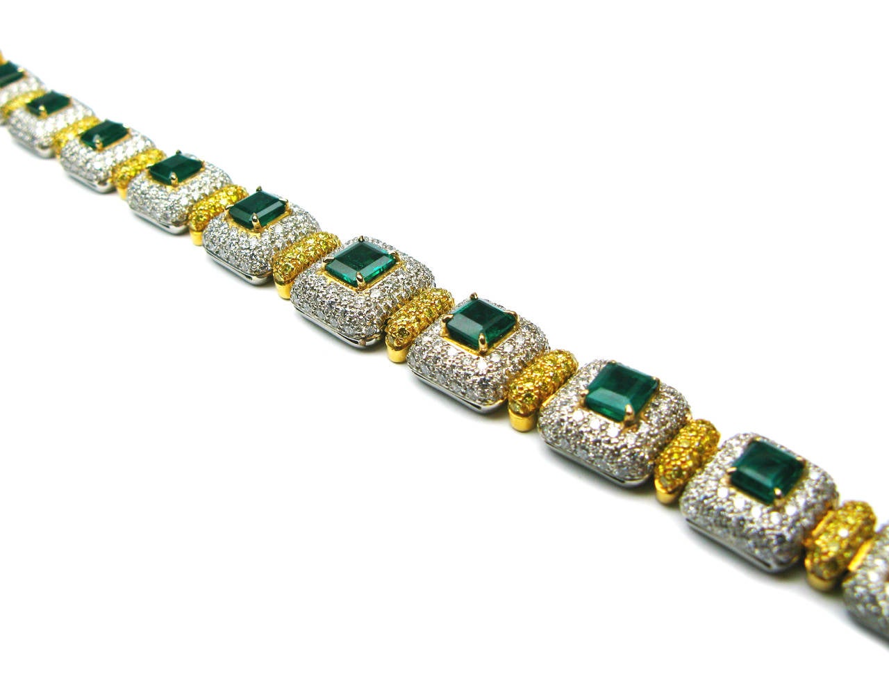 This one of a kind bracelet is a gorgeous combination of sparkle and rich, intense color. 9.63 carats of vibrant green emeralds are set in yellow gold against a glimmering background of white pave diamonds set in platinum. Each domed link contains