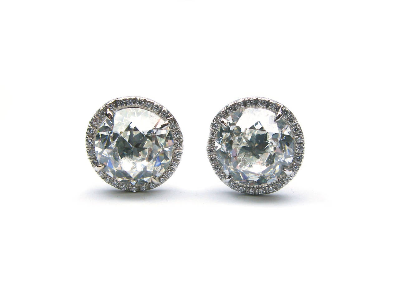 This spectacular pair of 18kt white gold diamond stud earrings features a GIA certified 4.40ct, H color, VS1 clarity Old European cut diamond and a GIA certified 4.58ct, H color, SI1 clarity Old European cut diamond with 0.21ctw diamond pave frames.