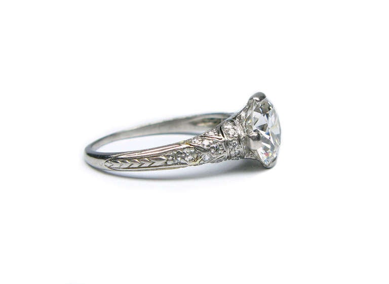 This platinum Tiffany & Co. signed unique Art Deco engagement ring features a G colored VS1 clarity, round brilliant diamond, measuring 1.76 carats. The delicate, semi bezel, pave ring is sprinkled with 26 smaller diamonds. The quality of this