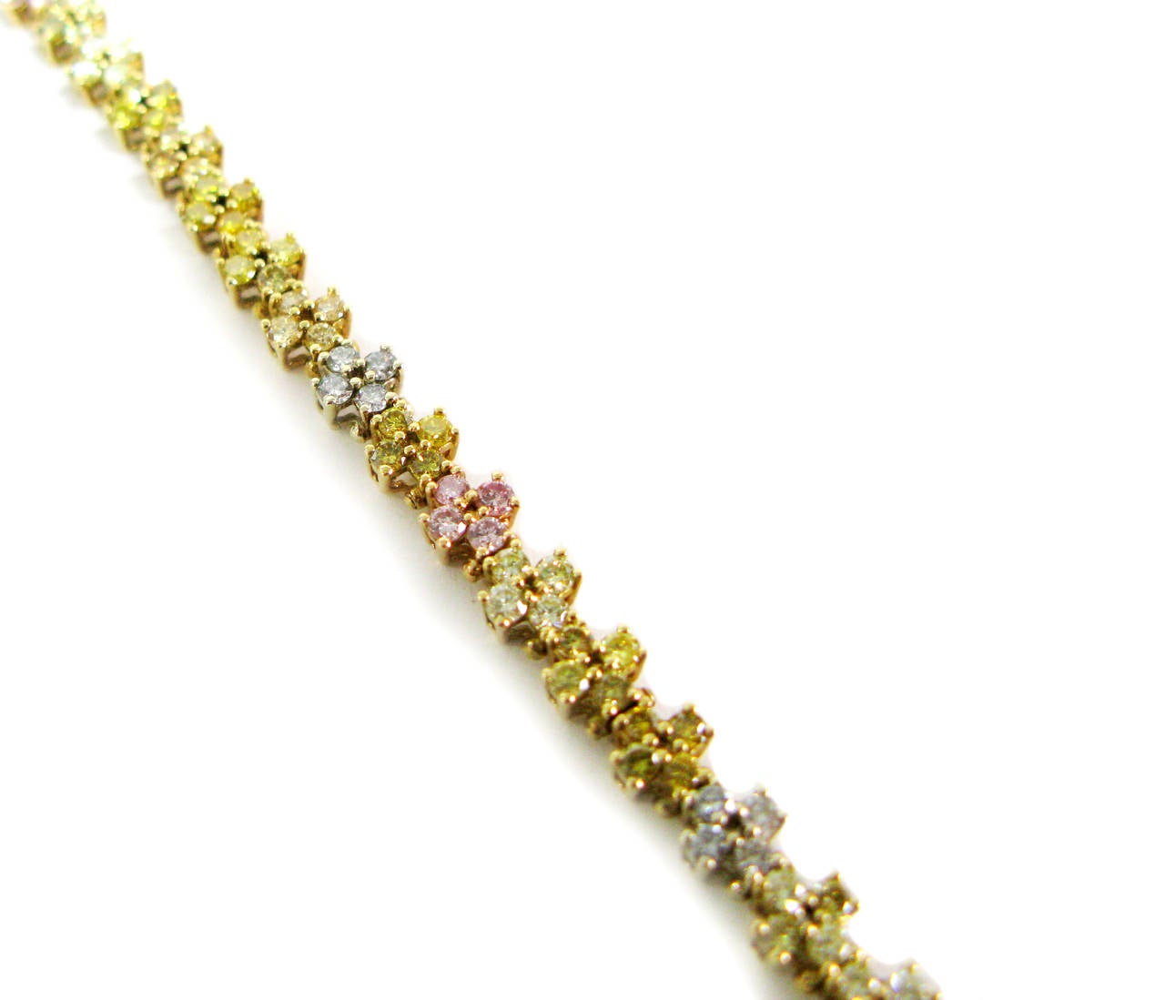 This unique 18kt tri-color gold piece offers a twist on the classic tennis bracelet. It features clusters of four round brilliant diamonds in natural fancy colors including yellow and pink mixed with white for a total carat weight of 4.40cts. This