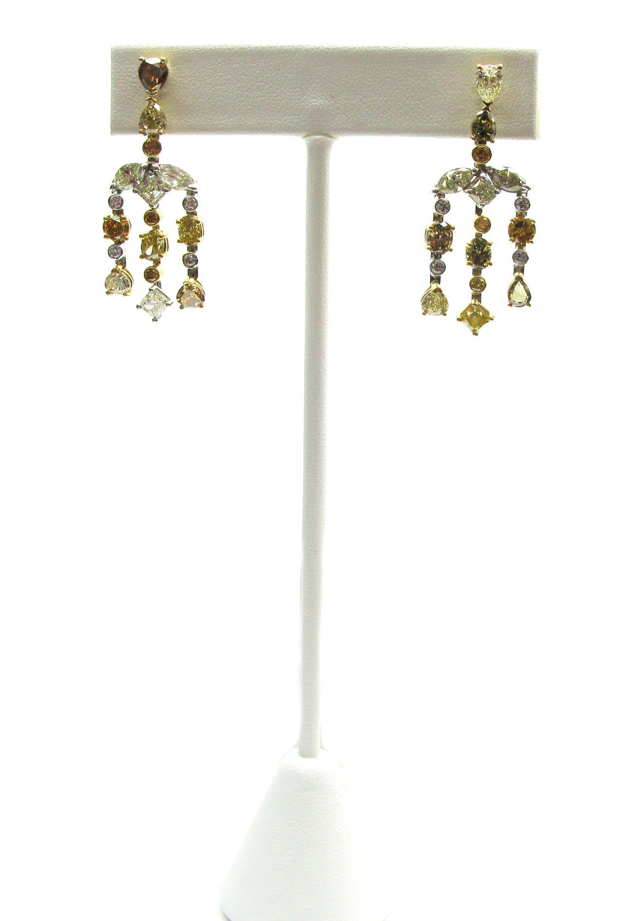 This 18kt two-tone gold handmade pair of 9.84ctw diamond chandelier earrings is truly one-of-a-kind. It features a mix of prong-set natural fancy colored diamonds in a variety of shapes and sizes with bezel-set round brilliant diamond set between