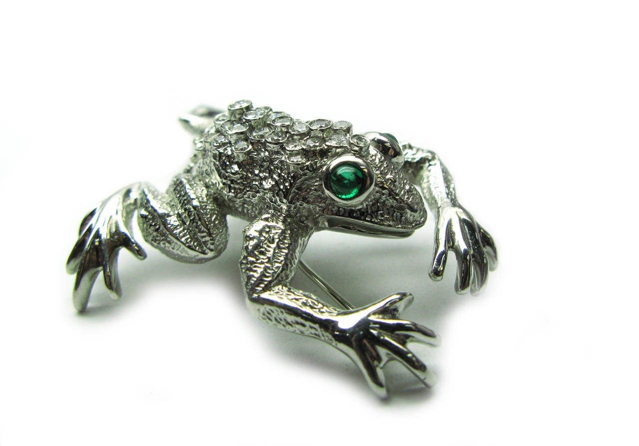 This platinum Kurt Wayne frog motif brooch contains 0.68ctw bezel set round brilliant diamonds and bezel set green emerald cabochon eyes weighing 0.21cts. This unique piece was created for a true animal lover!