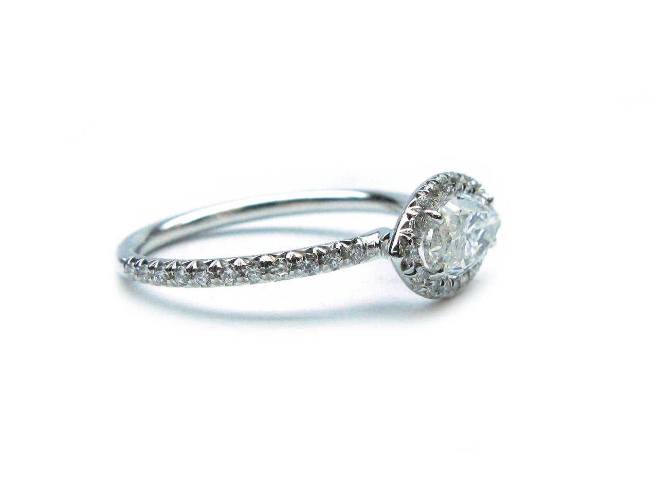 This lovely handmade platinum engagement ring features a horizontally set 1.01ct, I color, SI2 clarity, Marquise cut diamond center stone with a pave set round brilliant diamond halo and band with 0.28ctw of stones.This ring offers a unique twist