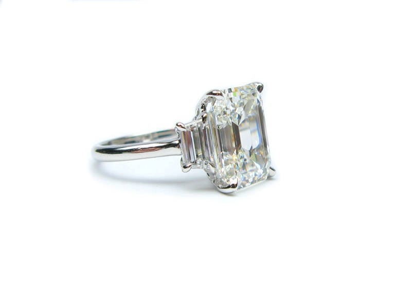 This GIA certified 6.11Ct, G color, VS1 clarity, emerald cut diamond engagement ring is set in platinum and flanked with 0.96Ctw E color VS quality traps. Elegant in all its simplicity, this piece is perfect for the lady with classic taste, but
