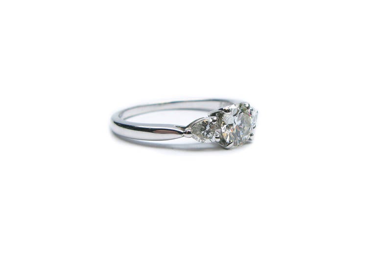 This delicate platinum Van Cleef & Arpels signed engagement ring features a lovely GIA certified 0.77Ct F color VVS2 clarity round brilliant diamond. It is flanked by two pear shaped diamonds weighing 0.34ctw. This truly classic piece is just as