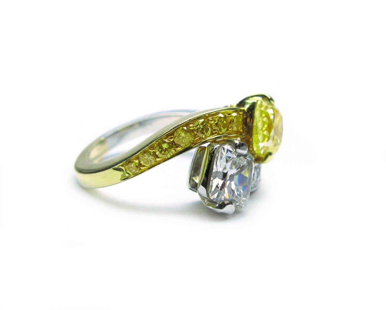 This beautiful one-of-a-kind handmade platinum and 18kt yellow gold twin ring features a 1.25ct, natural fancy yellow color, VS2 clarity, cushion cut diamond and a 0.83ct, G color, SI1 clarity, cushion cut diamond accented with natural fancy yellow