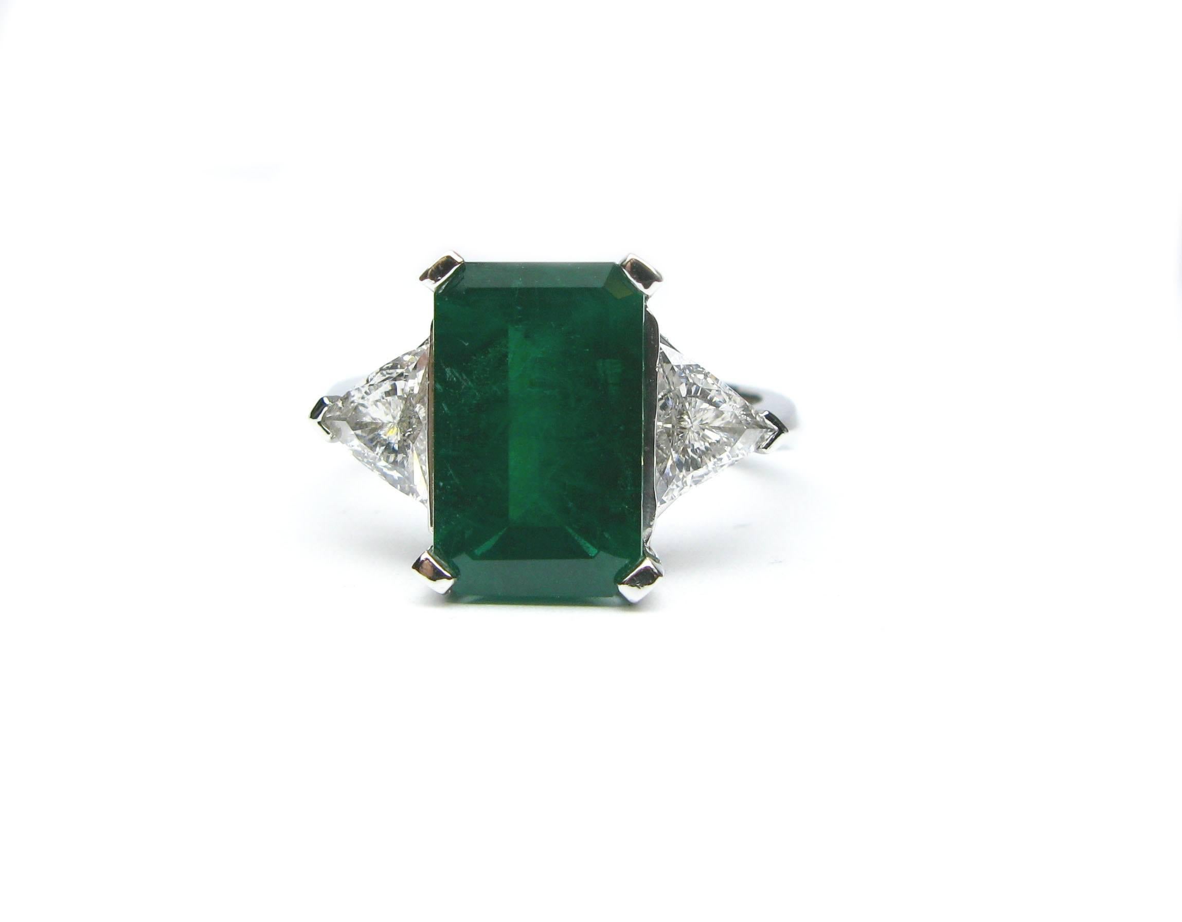 This stunning platinum ring features a gorgeous 3.98ct rectangular step cut emerald center stone. The rich green color of this gemstone pairs nicely with the 0.81ctw, G color, VS1 clarity, trillion diamond sidestones and the 0.20ctw pave diamond