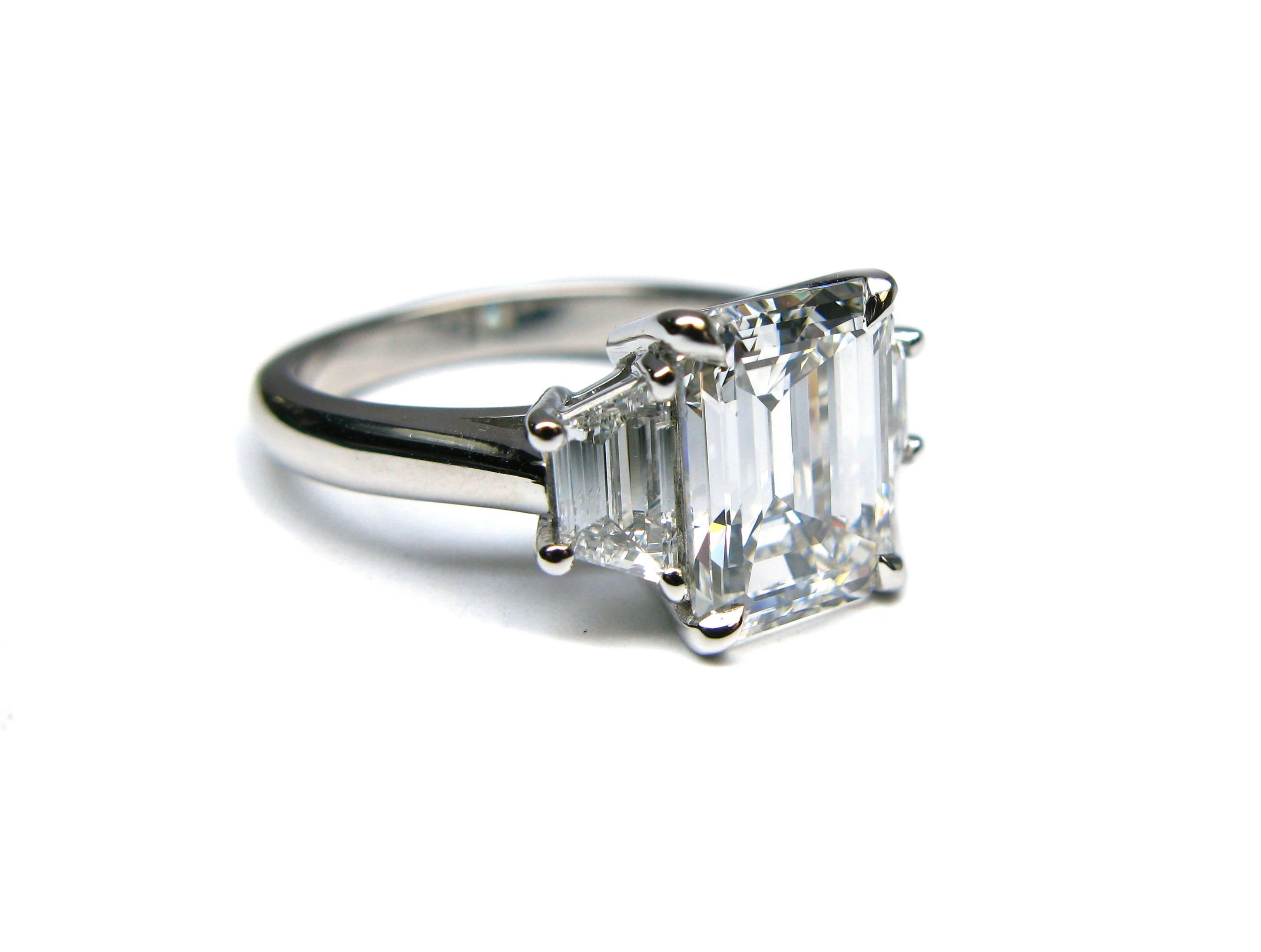 This stunning handmade platinum engagement ring features a GIA certified 3.13ct, G color, VS1 clarity, Emerald cut diamond center stone with 0.65ctw, G color, VVS clarity, step cut trapezoid diamond sidestones. This beauty will belong to one lucky