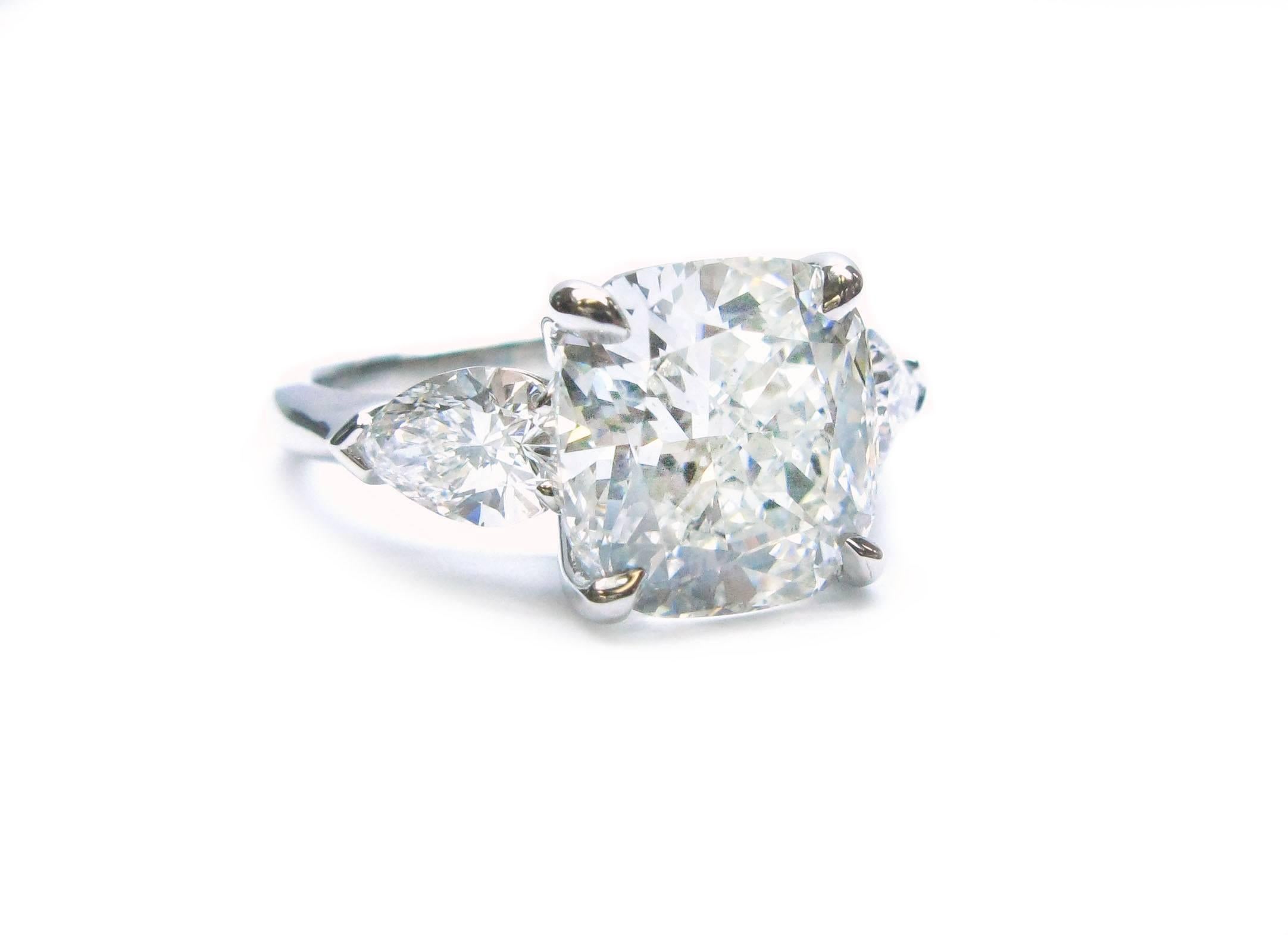 This spectacular handmade platinum ring features a GIA certified, 5.05ct, H color, SI1 clarity, Cushion Modified Brilliant cut diamond center stone with approximately 1.20ctw pear shape diamond sidestones. This gorgeous ring will be the perfect
