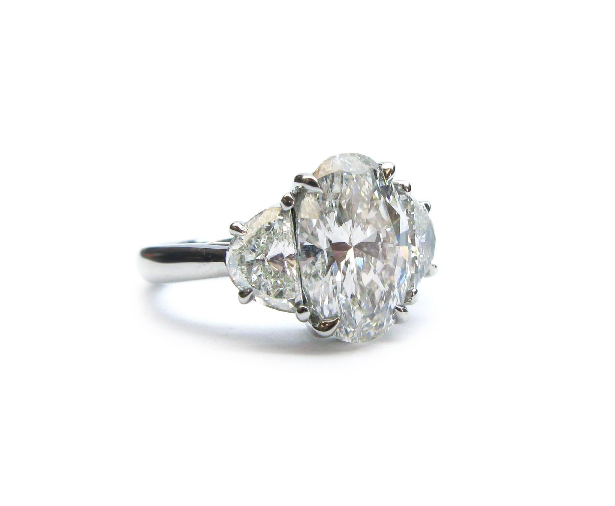 This beautiful handmade platinum ring features a GIA certified 3.04ct, G color, VVS2 clarity, Oval cut diamond with 1.12ctw halfmoon diamond sidestones. This sparkling stunner belongs on your lovely finger!