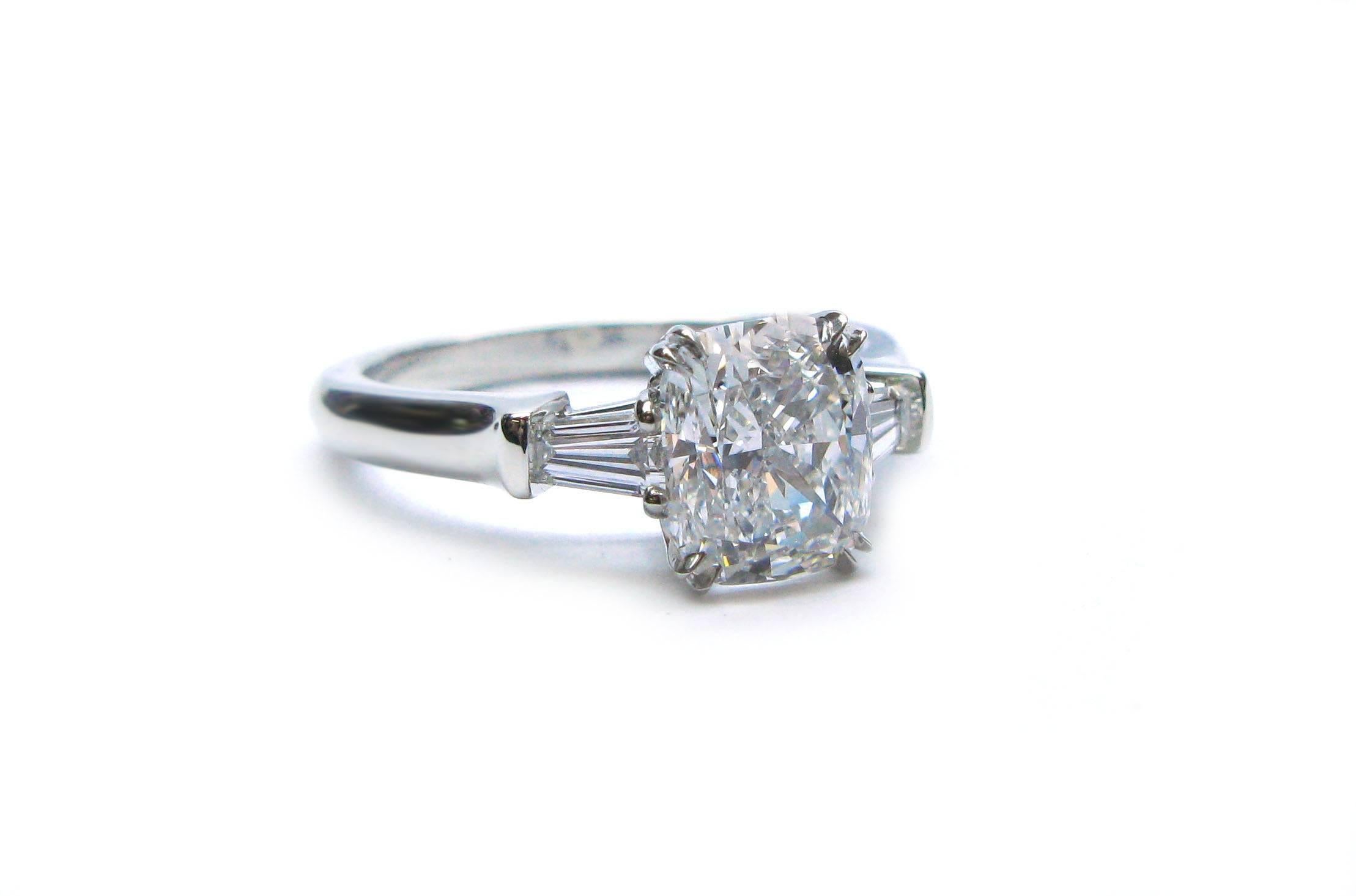 This lovely Harry Winston signed platinum engagement ring features a GIA certified 1.70ct, F color, VS1 clarity, Cushion cut diamond center stone with tapered baguette diamond sidestones. With this stunning ring on her finger she will be the envy of