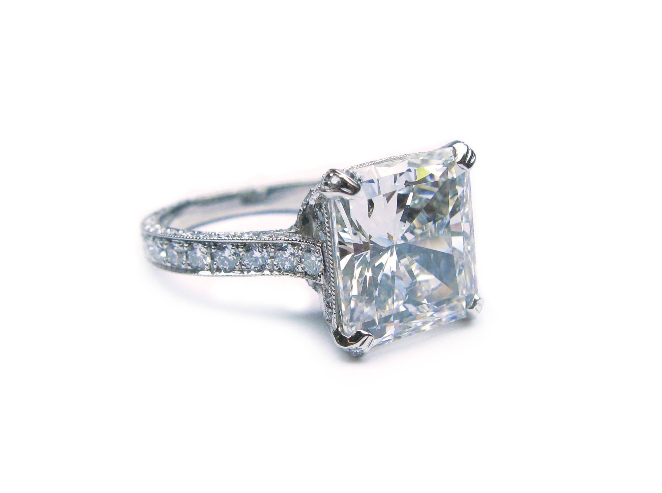 This spectacular handmade platinum engagement ring features a sparkling GIA certified 6.14ct, H color, VS1 clarity, Radiant diamond center stone set with approximately 2.00ctw of pave set round brilliant diamonds around the head and in the band.