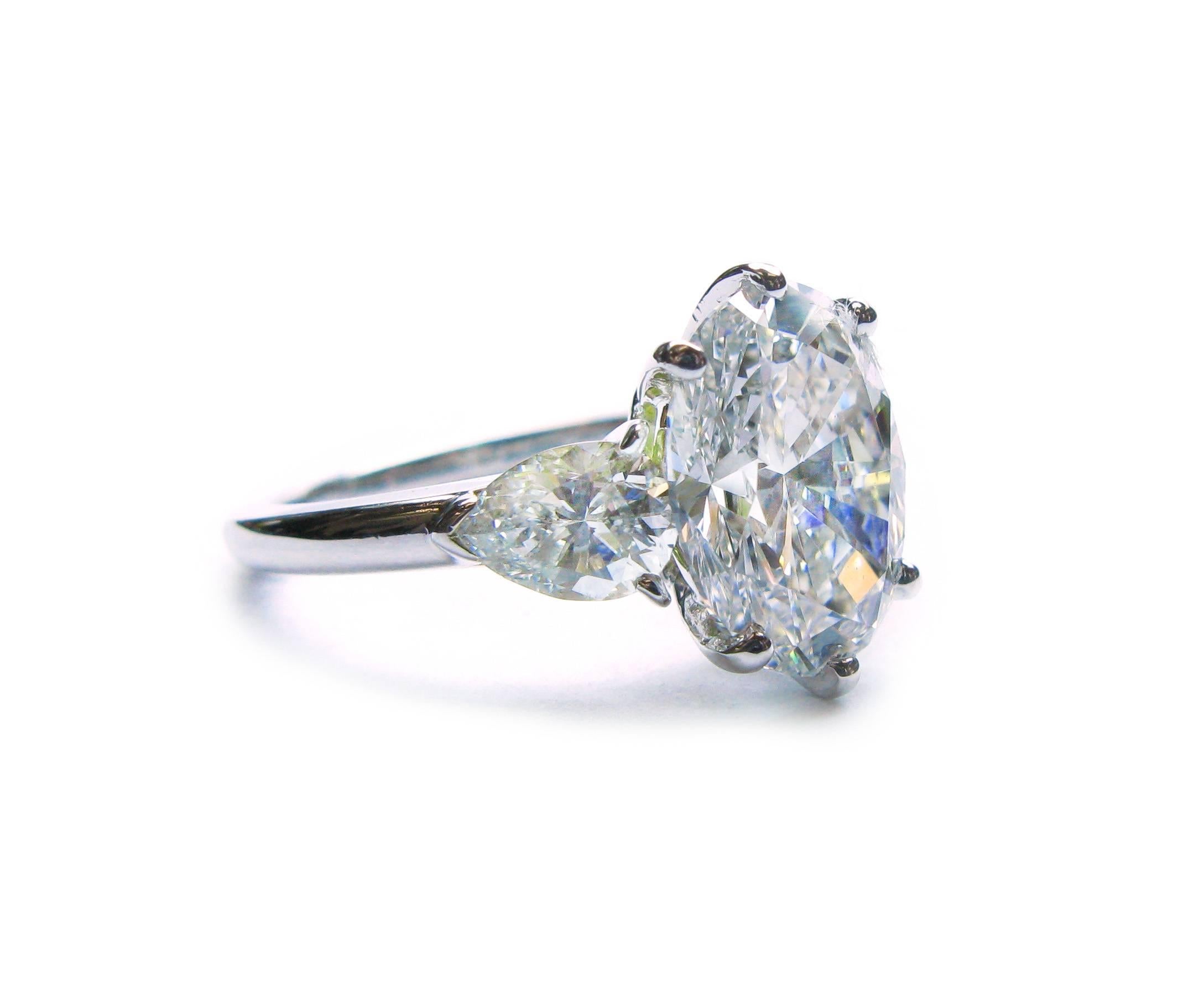 This beautiful 18kt gold Van Cleef & Arpels engagement ring features a GIA certified 3.01ct, E color, VS2 clarity, Oval cut diamond center stone with approximately 0.90ctw pear cut diamond sidestones. This classic stunner will be the perfect