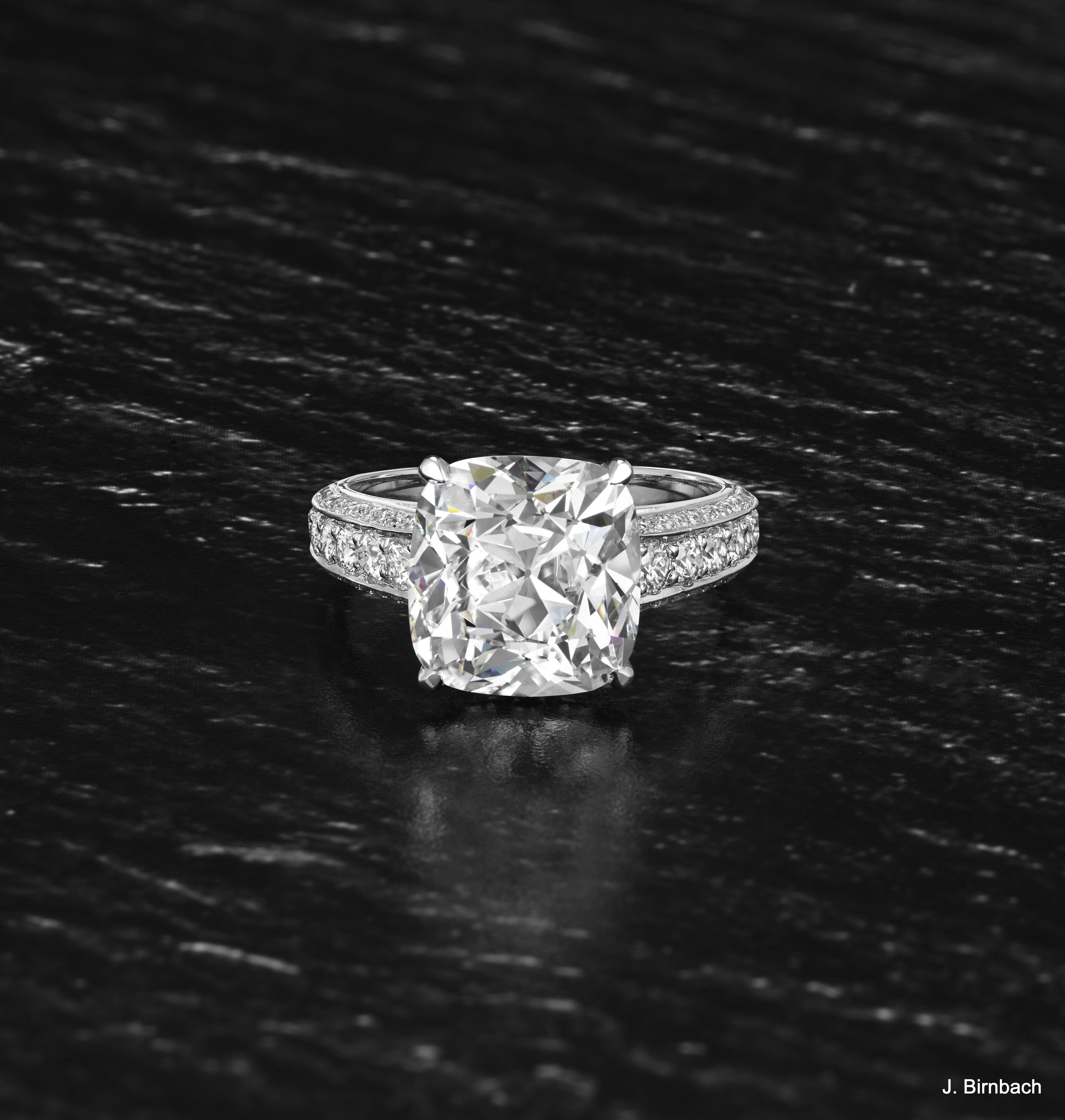 This stunning handmade platinum ring features a 6.06 carat cushion brilliant-cut center diamond with E color and VS1 clarity. The band contains 1.15 ctw round brilliant diamonds adorning the band on all three sides. This magnificent piece will
