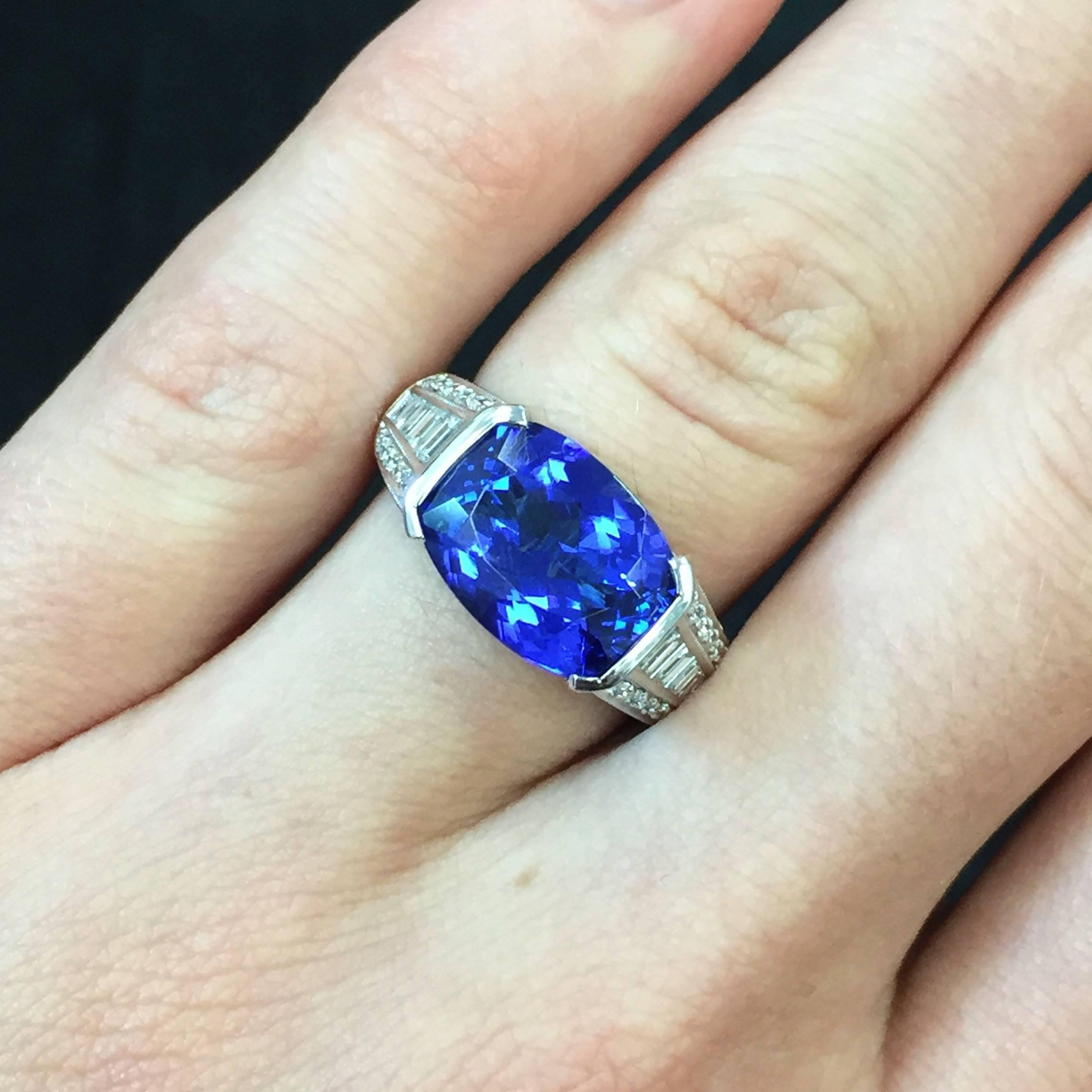 A lovely and lively 4.10 cushion-cut tanzanite is semi-bezel set into an intricate 18k white gold ring with over 1.50 carats of baguette and round-cut diamonds accenting the shoulders and elaborate gallery.
