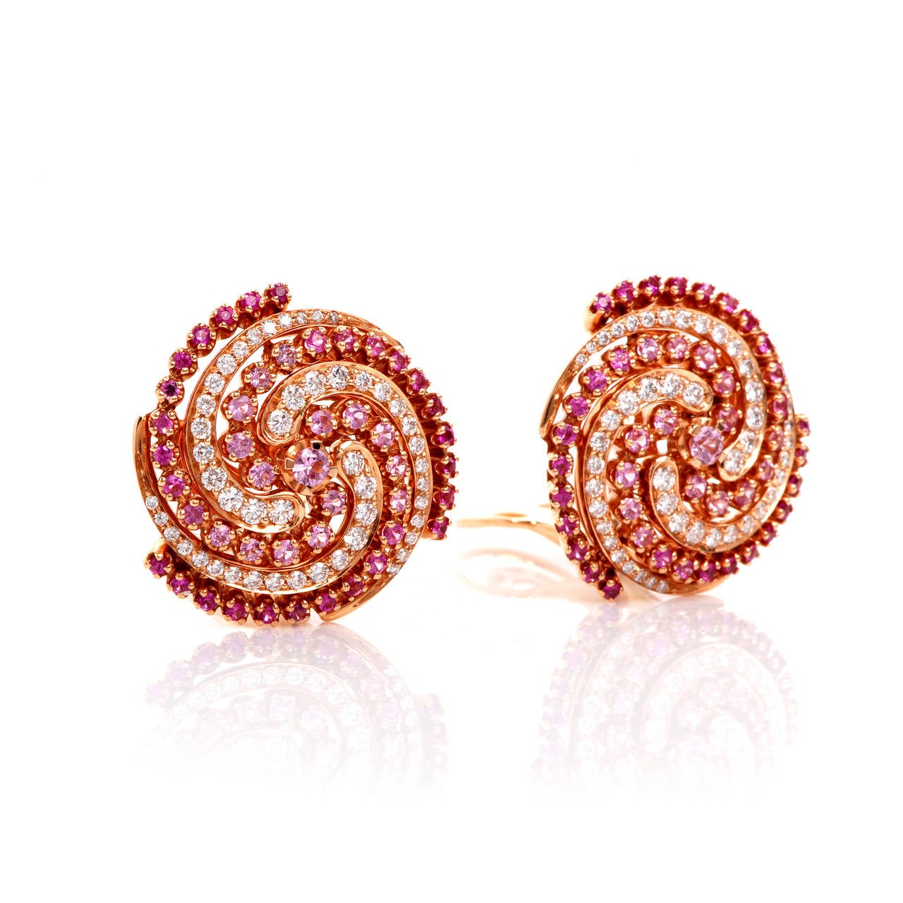 These stunning and very unique Garavelli designer swirl clipback earrings are crafted in solid 18K gold. These earrings are accented with some 96 genuine round cut diamonds approx 2.00cttw, F-G color, VVS clarity and some 92 genuine pink sapphires