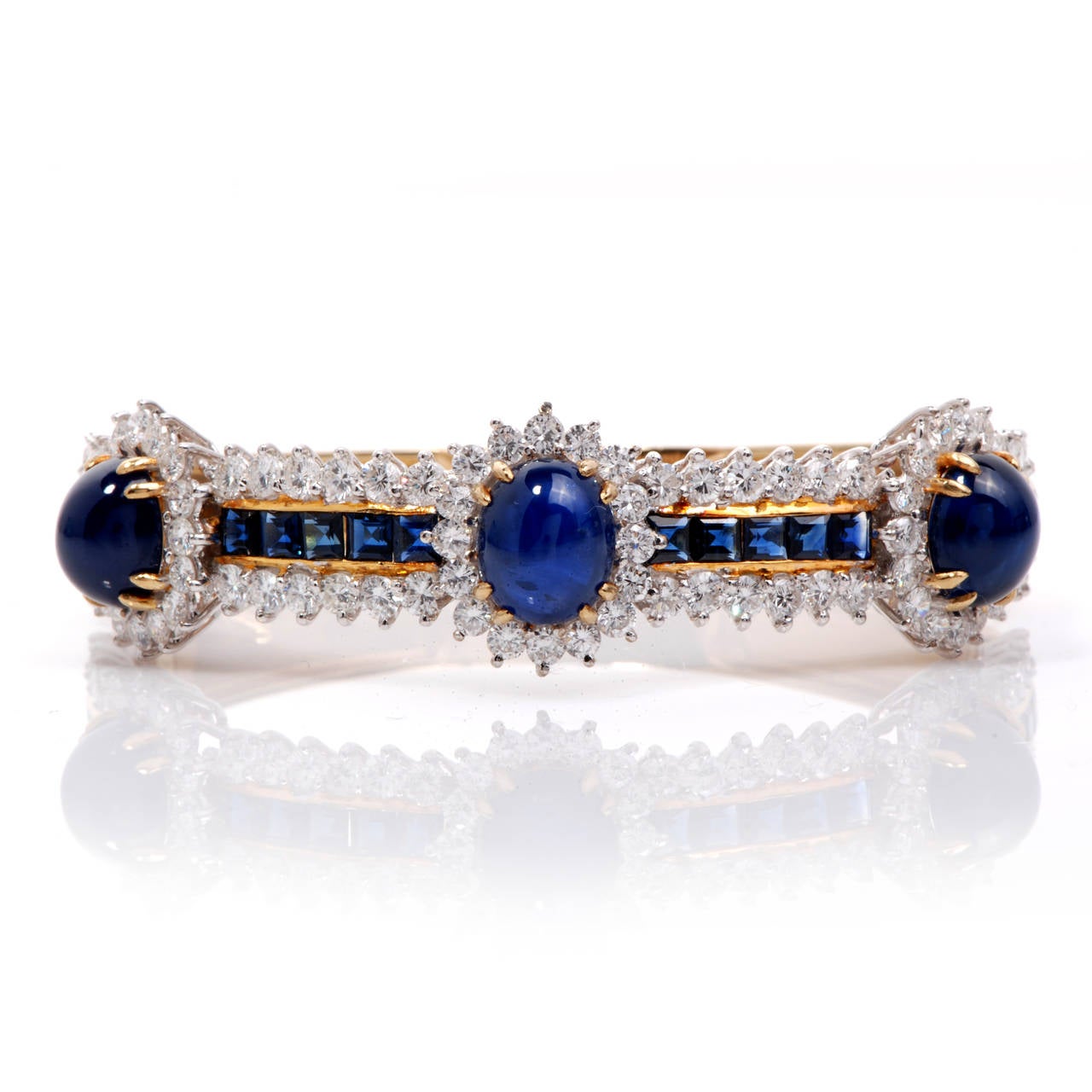 This stunning and elegant sapphire bangle bracelet is finely crafted in solid 18K yellow and 18k white gold. This glamorous bracelet is accented with 82 brilliant genuine round cut diamonds approx. 5.25 ct, G color, VS clarity. Topped with  3 oval