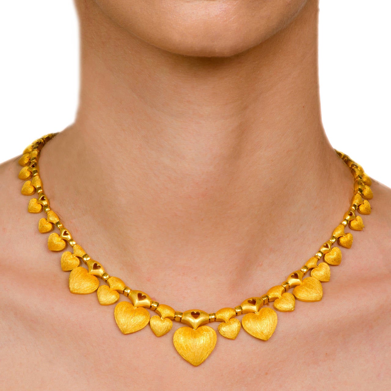 This elegant estate necklace with romantic heart motif pendants  is crafted in solid 24k  yellow gold.  This immaculately crafted  necklace incorporates a gold chain from which  suspend  delicate heart-shaped silhouettes of different sizes, with the