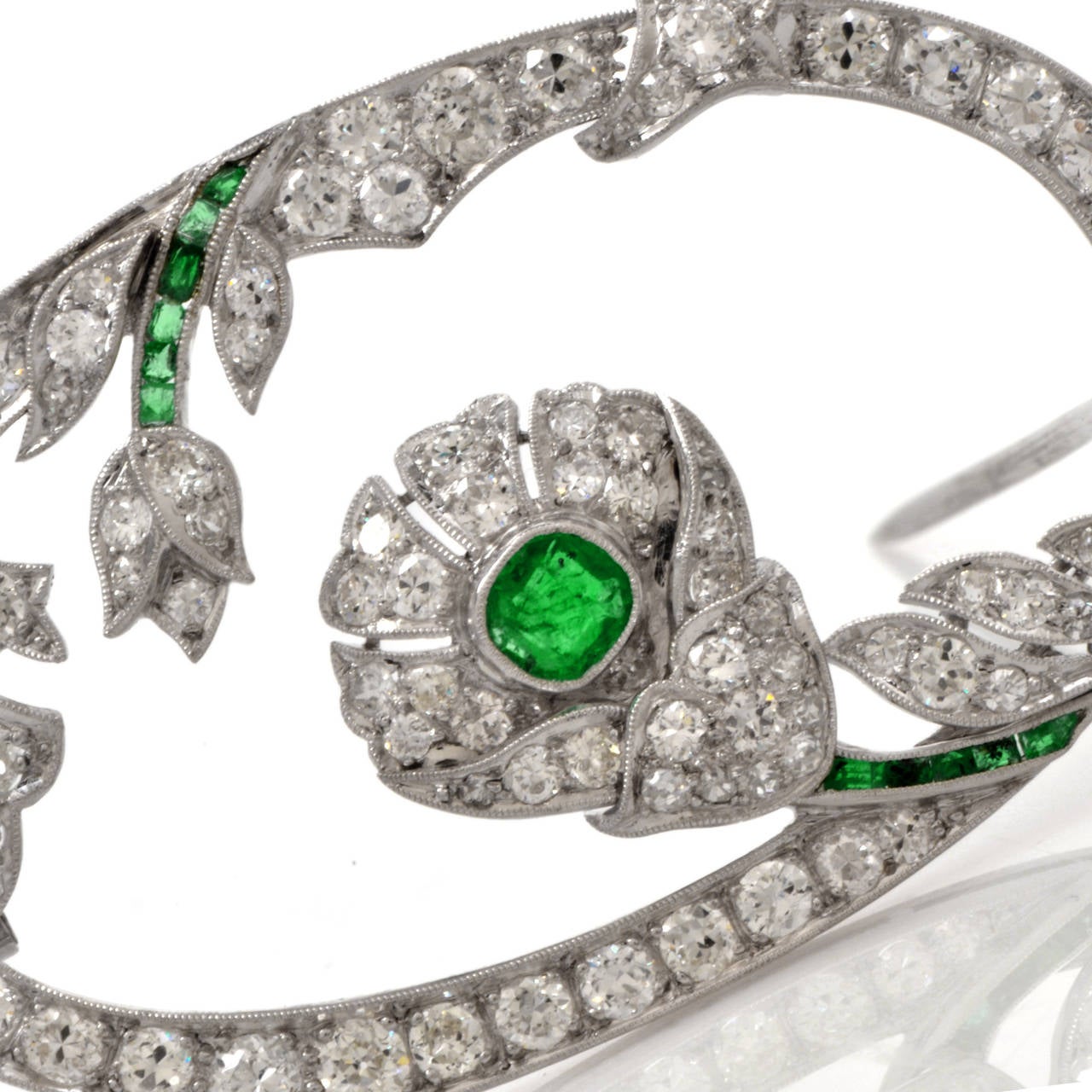 This captivating Antique Art Deco brooch Pin is crafted in solid platinum. This brooch is cumulatively enriched with genuine round European cut diamonds approx: 3.85cttw, G-H color, VS clarity and one cushion-cut and 12 tapered baguette Green