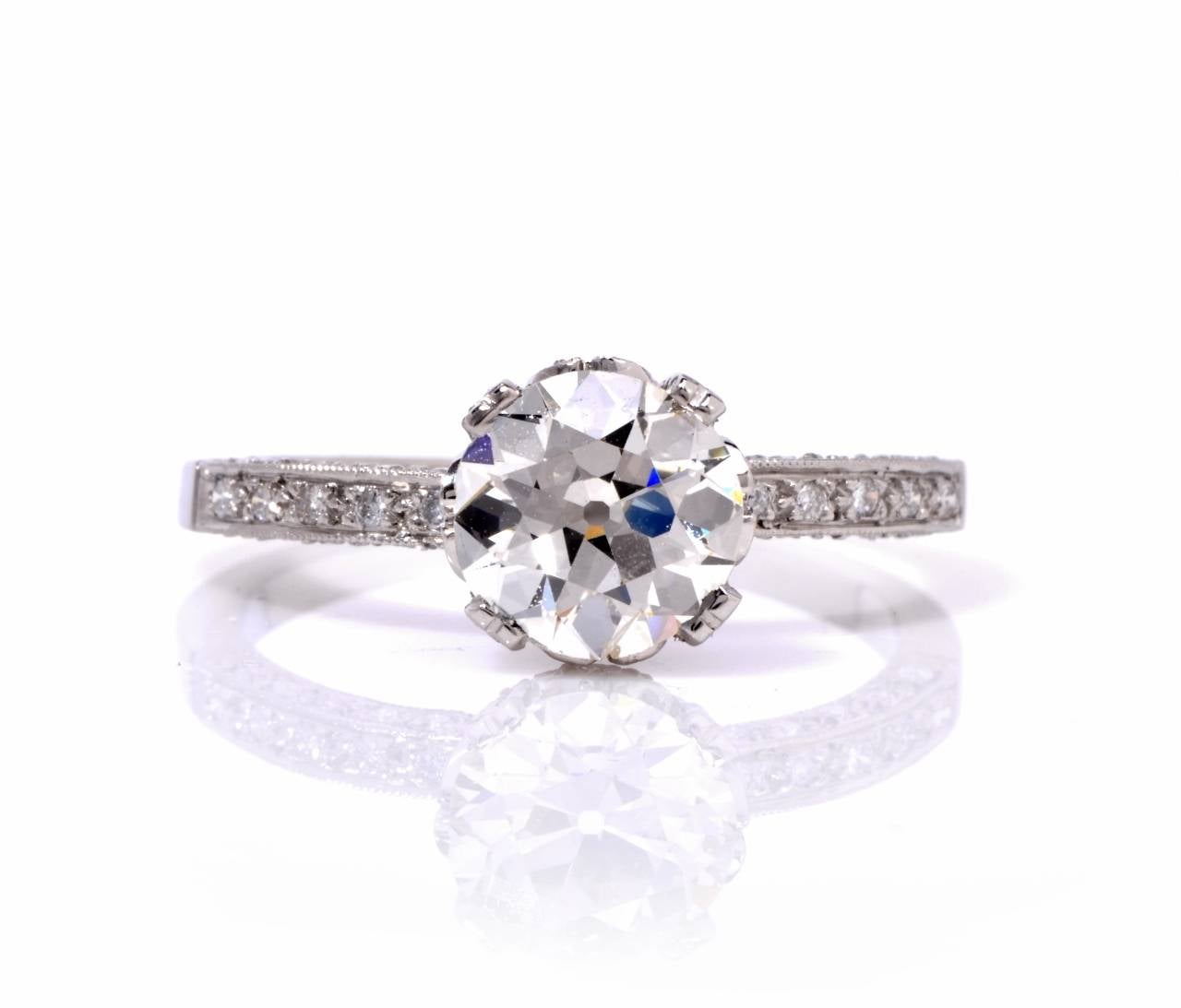 This vintage engagement ring with notable  brilliance and classic distinction   is  crafted in solid platinum, exposing a  genuine old European cut diamond of approx. 1.58 cts,  graded I color and VS clarity. An assemblage of 51 genuine round cut