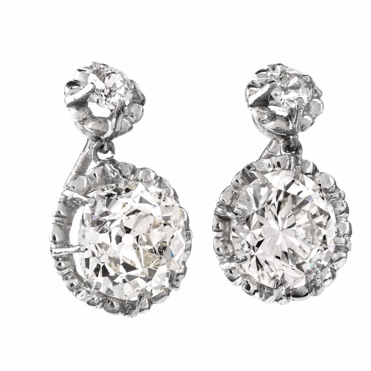These captivating vintage earrings are crafted in platinum, weigh cumulatively 6.8 grams and  each measure 18 mm long.  The two large diamonds weigh cumulatively 6.05 carats in total  and are graded I - J color and VS2 to SI1 clarity.  And two