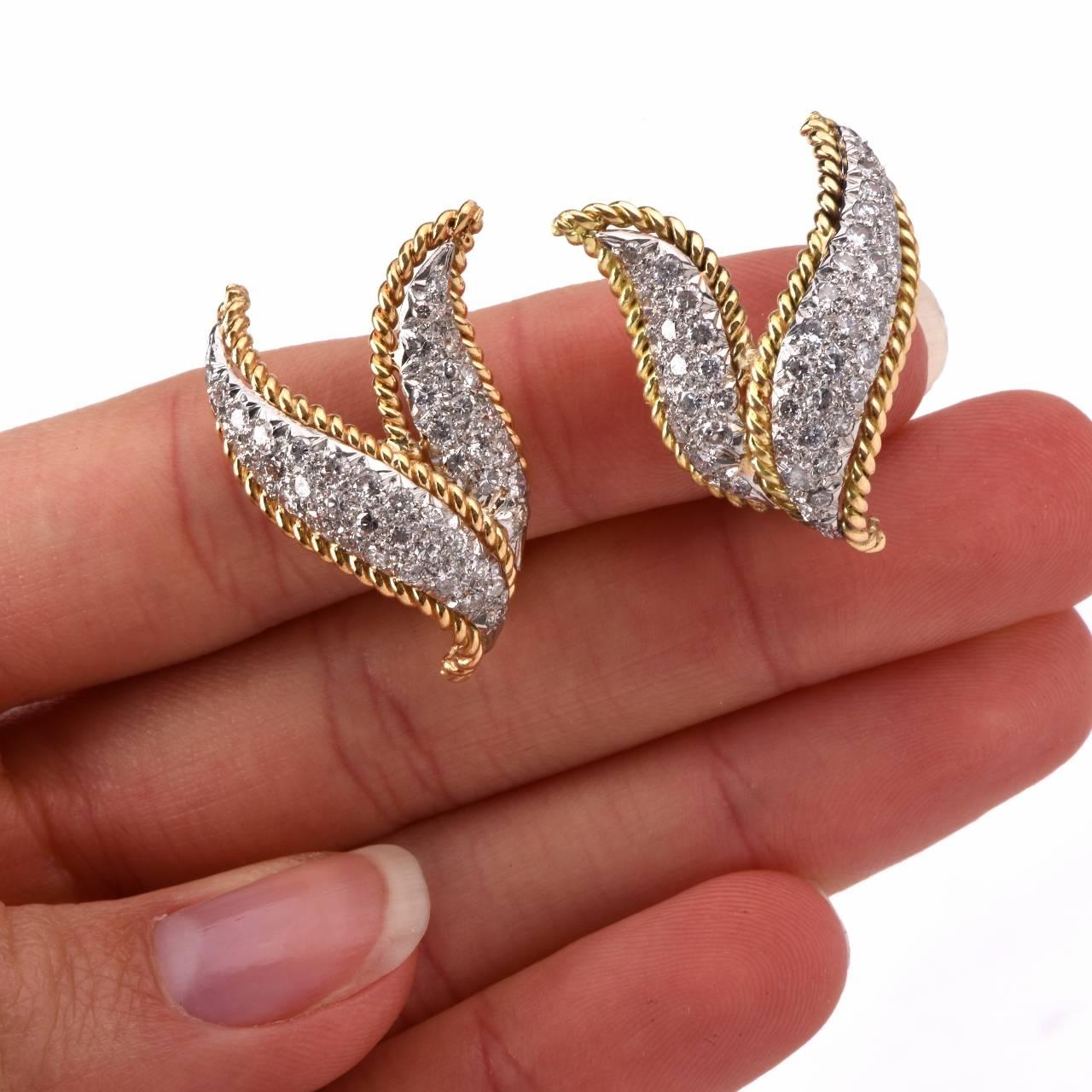 These timelessly elegant and enchanting estate earrings are crafted in a combination of solid 18K white and yellow gold, weigh 14.1 grams and measure 28 x 22 mm. These earrings are designed as a pair of diamond-swathed, gracefully scrolled leaves, 