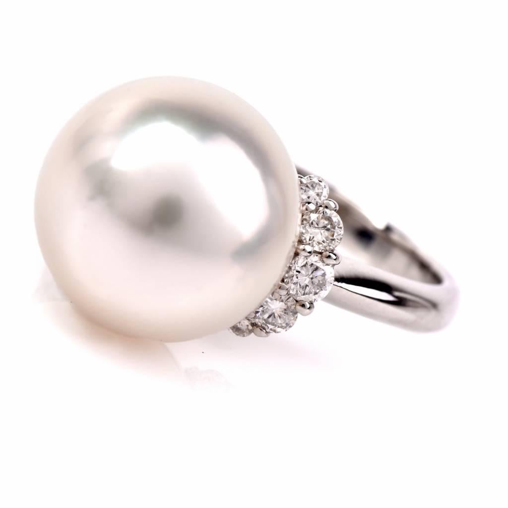 This South Sea pearl and diamond cocktail ring is crafted in solid platinum and weighs 7.4 grams. This classically elegant and timeless cocktail ring exposes a lustrous 12 mm South Sea pearl of ‘white with some pinkish hue’ color.  It is flanked by