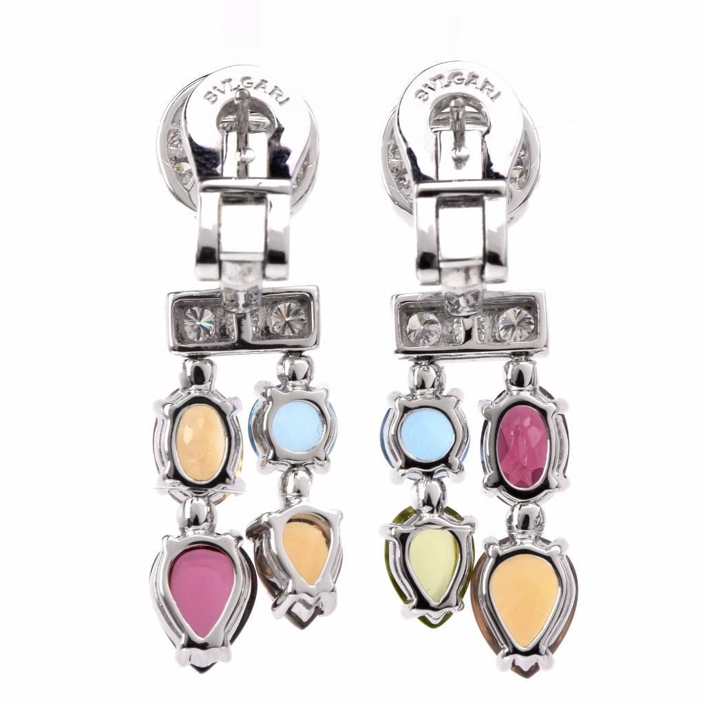These authentic Bvlgari gold and gemstone dangle earrings of bold and vivacious aesthetic are crafted in solid 18K white gold and expose an assemblage of colorful cabochon gemstones. exposed as cascading pendant components. The gemstones include