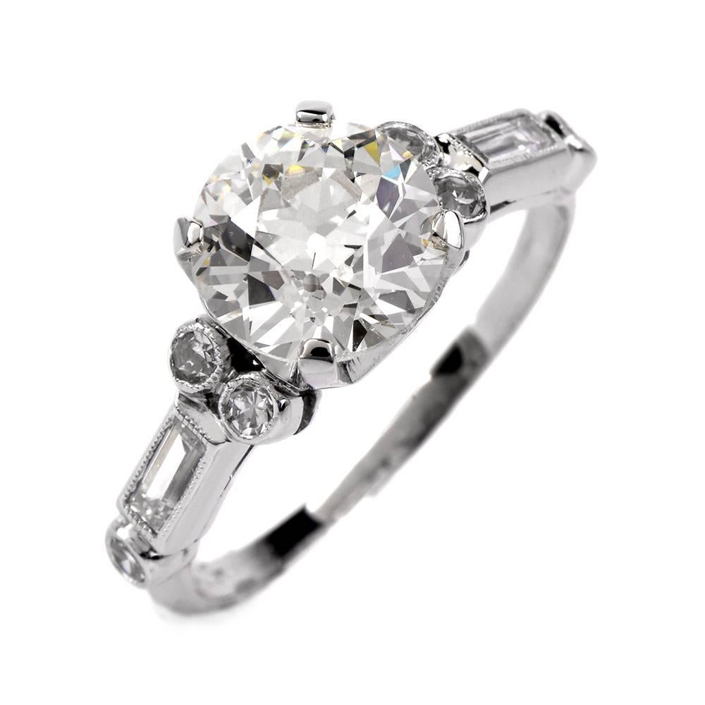 This exquisite antique  diamond engagement ring of unmatched refinement is crafted in solid platinum, exposing a breath-taking 1.98-ct round old European-cut diamond,  mounted within an ornate setting with hexagonal profiles on both sideds. The high