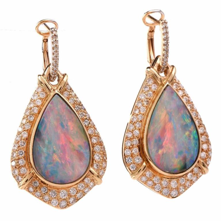 These enchanting vintage pendant jacket earrings are crafted in 14K yellow gold and feature 2 genuine pear shape opal cabochons weighing approx: 6.30cts, bezel set in yellow gold. These captivating  earrings are resplendent in a total of 142 genuine