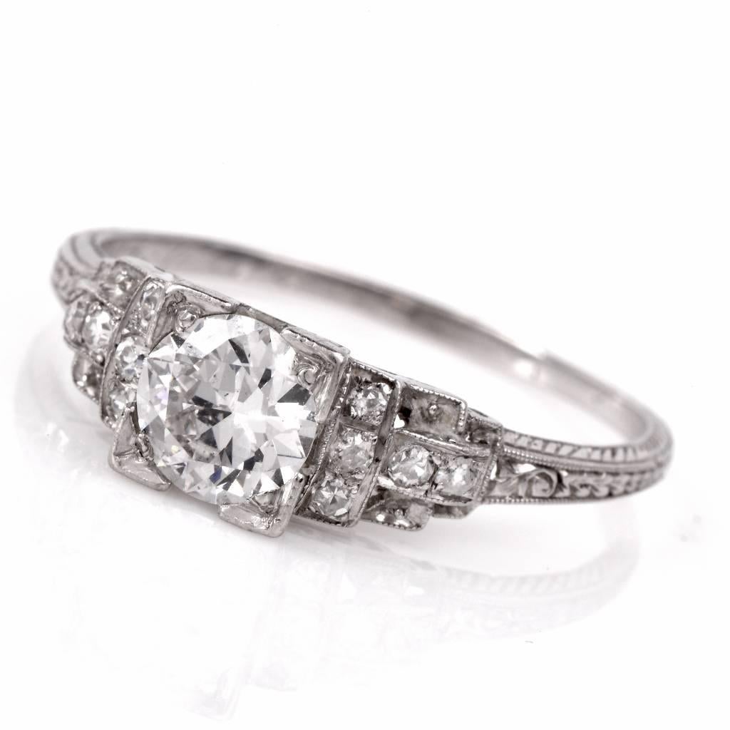 This Antique Art Deco diamond engagement ring is hand crafted in solid platinum. It centers an eminent 0.80 ct round European-cut diamond monuted within a geometrically inspired square setting. The center-stone is flanked by diamond-studded