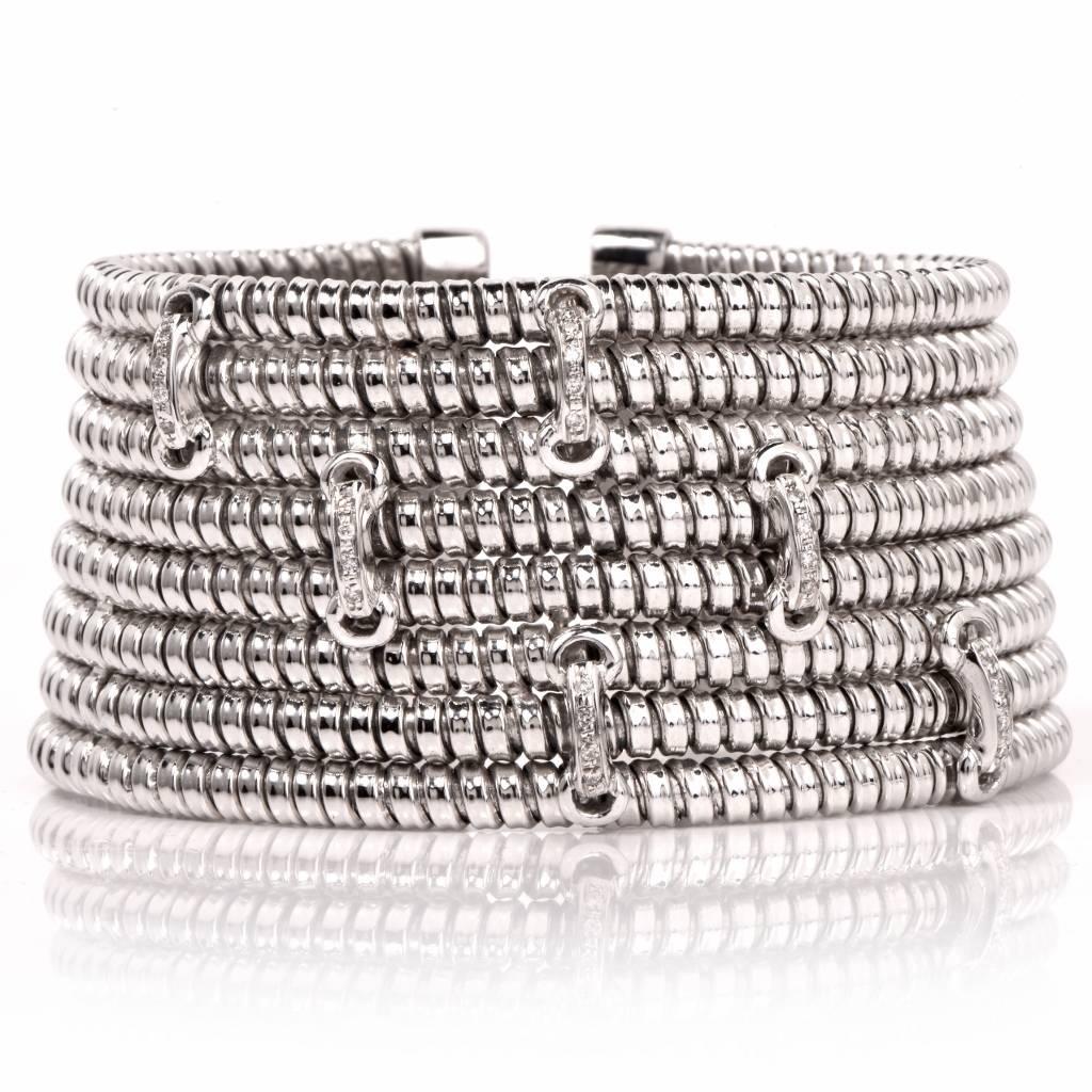 This immaculately designed wide cuff bracelet of Italian provenance is inspired by the Pharaonic style of cuff bracelets, crafted in artfully patterned 18K white gold. It consists of an assemblage of 8 rows enriched with 24 round cut genuine
