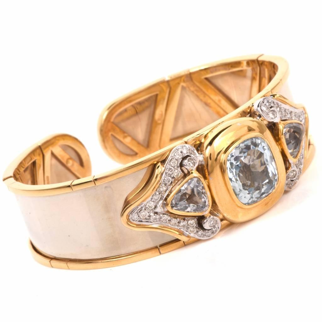 This estate bangle cuff bracelet is crafted in solid 18K polished yellow gold. It exposes a sizable cushion-cut aquamarine of a tender pastel blue color, mounted within yellow gold frame and 2 triangular genuine aquamarines weighing approx.