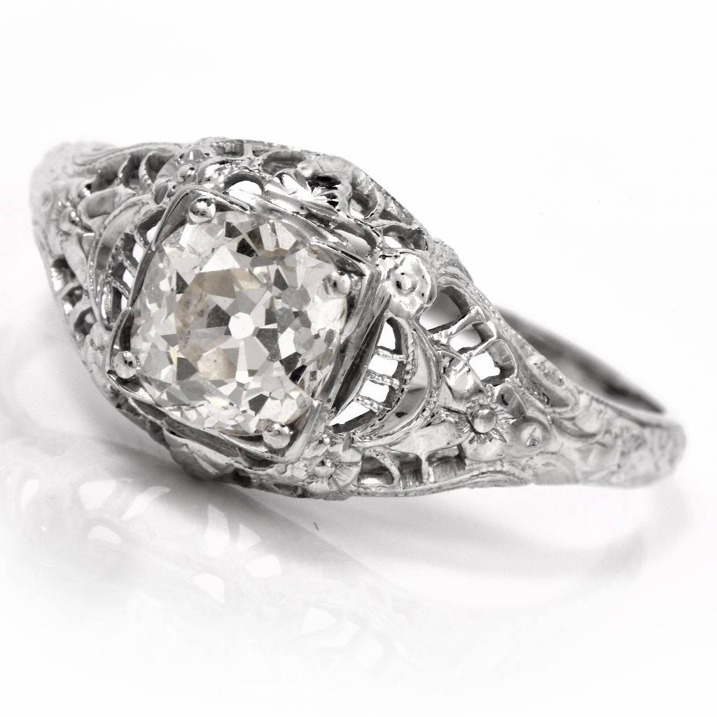 This antique solitaire diamond engagement ring is hand crafted in solid 18K white gold. It centers a prominent old-mine diamond of 1.35cts, graded J-K color and VS1 clarity.  The solitaire antique old-mine diamond is set in a subtly elevated