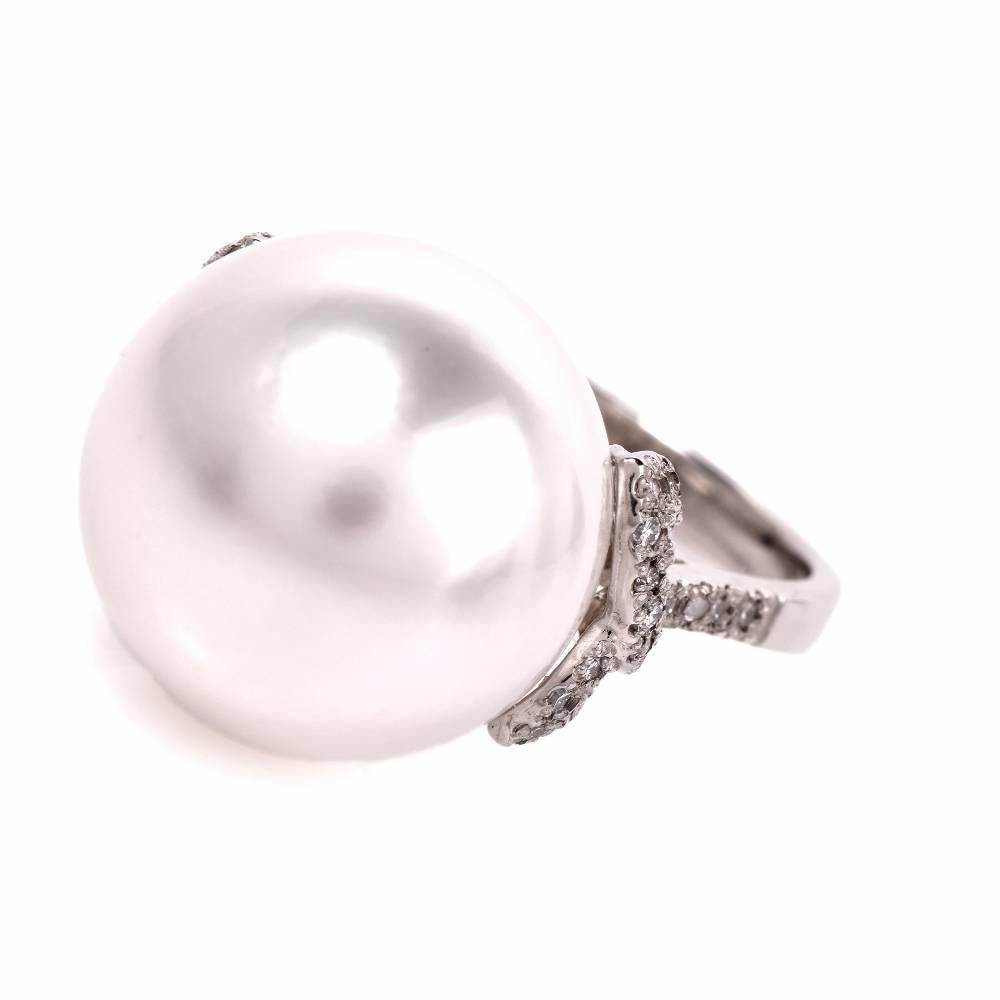 This South Sea pearl and diamond cocktail ring is crafted in solid platinum and weighs 7.4 grams. This classically elegant and timeless cocktail ring exposes a lustrous 12 mm South Sea pearl of ‘white with some pinkish hue’ color.  It is flanked by