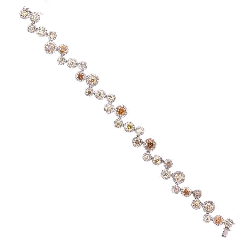 This sparkling GIA graded diamond bracelet is crafted in solid 18K white gold. This enchanting bracelet features a bubble design accented with 35 Natural Fancy Colored Diamonds, 3 of which has been graded by GIA. One is a Natural Fancy Deep