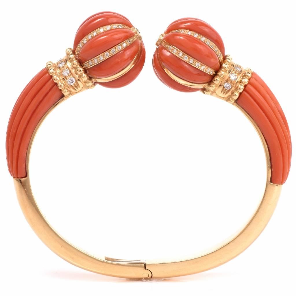 This captivating Italian made estate cuff bracelet is crafted in solid 18K yellow gold. The bracelet exposes at both open ends  beautifully crafted and ornately 'striped' carved red natural coral profiles, adorned with  rows of pave diamonds on