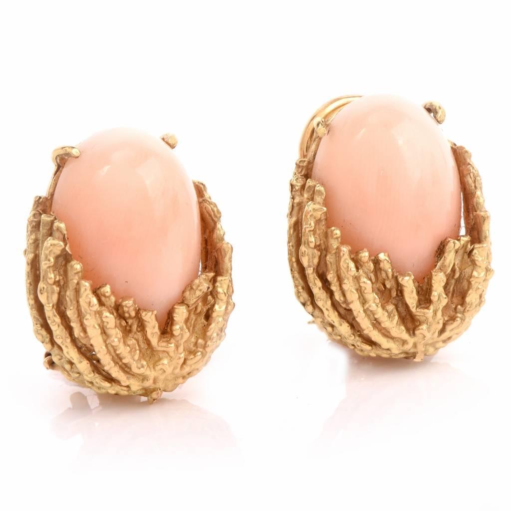 These clip-back earrings are crafted in solid 18K yellow gold and expose a pair of rare ‘angel skin’ coral cabochons. The enchanting pastel color gemstones are mounted within textured matted yellow gold. These stylish earrings feature clip-backs