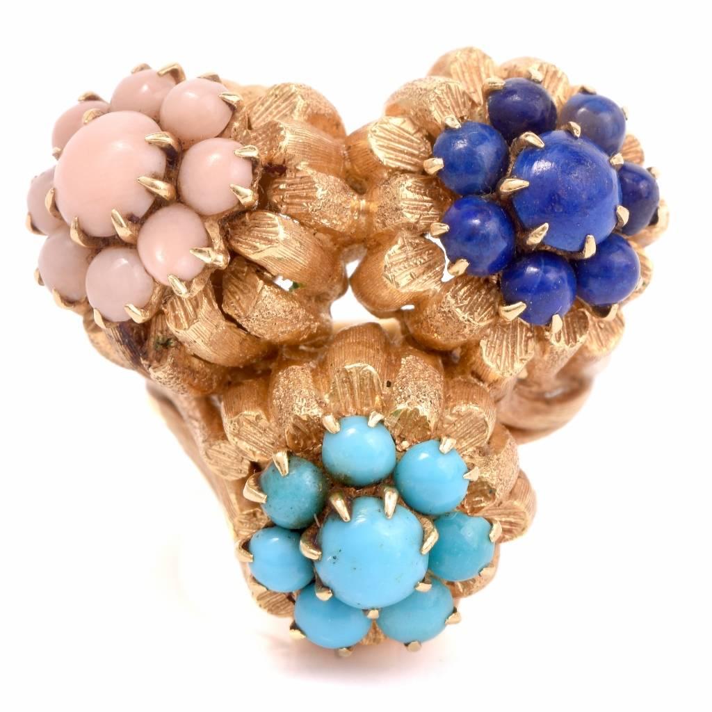 This enchanting circa 1950’s cocktail ring is crafted in solid 18K yellow gold. It is designed as cluster of three flowers adorned with angel skin natural coral, persian turquoise, and  lapis lazuli round cabochons. With a sizable shank, stamped