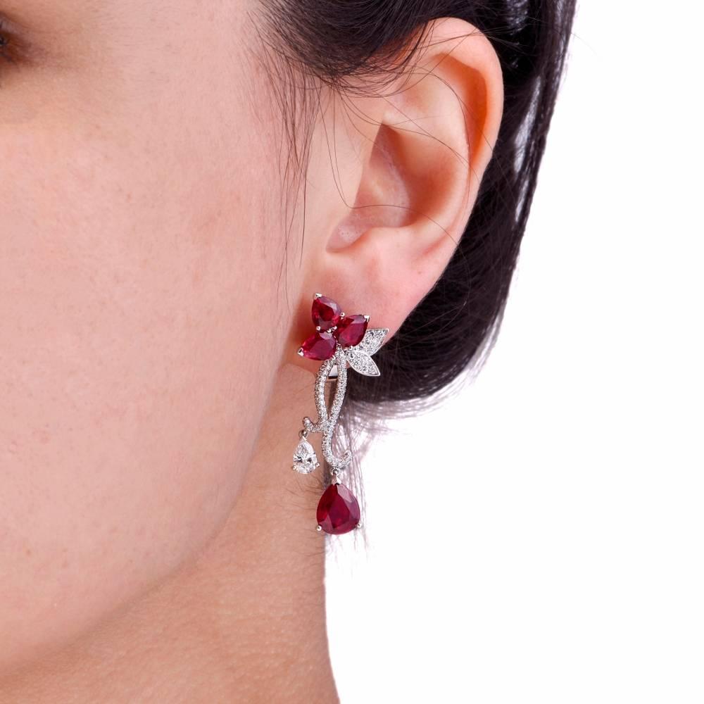 These stunning French made 18K white gold earrings feature a beautiful flower design adorned with 8 genuine pear cut Rubies (with natural inclusions and minor heat treatment approx: 9.75cttw, prong set; 2 genuine pear cut Diamonds approx: 0.73cttw,