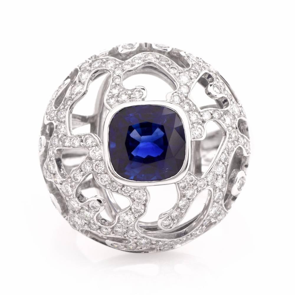 This artfully crafted cocktail ring is constructed  in solid 18K white gold and is centered with an eye-catching approx. 3.25 ct cushion-cut sapphire mounted within a fine bezel. The natural corundum is surrounded by diamond-studded openwork
