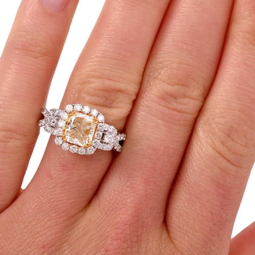 This modern engagement ring is crafted in solid 18K white gold. It centers a natural fancy light yellow diamond approx: 2.09cts, VS2-SI1 clarity, secured by four paw-prongs in 18k yellow gold. The center stone is surrounded by a halo of
