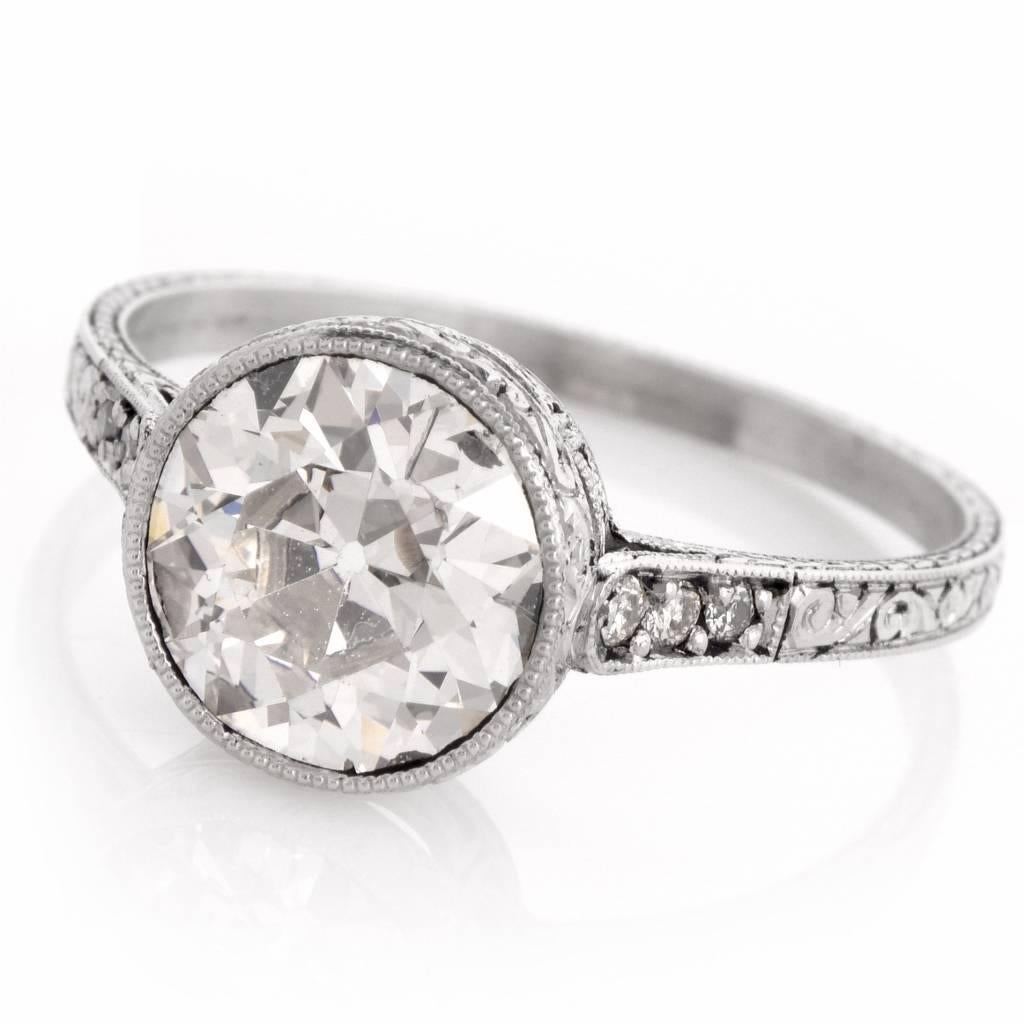 This antique engagement ring with highly elaborate details in workmanship is crafted in platinum. This Art deco ring exposes a 2.21 ct round-cut diamond graded I-J color and SI1 clarity, mounted within a delicately chiseled crown-shape setting.
