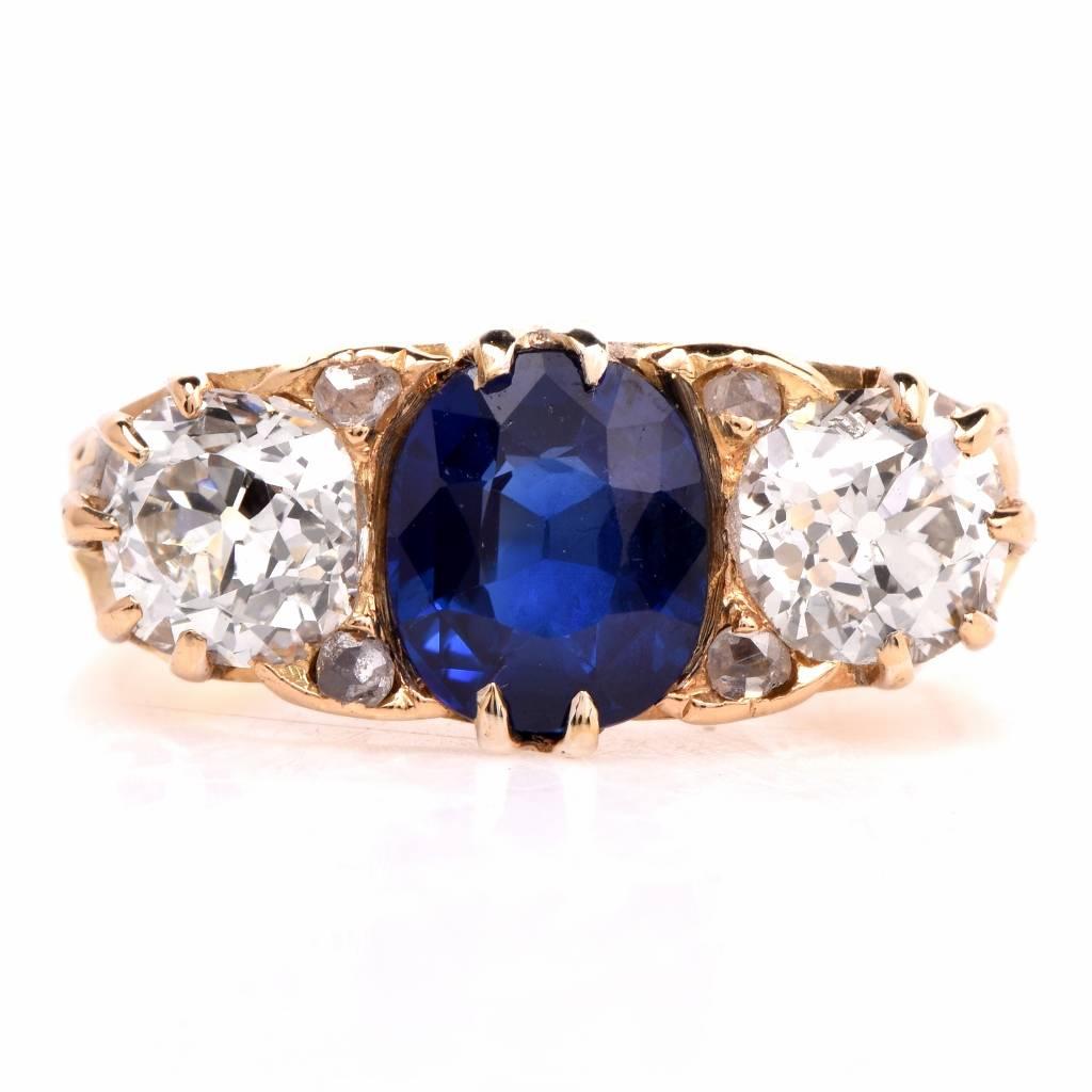 This exquisite antique ring is crafted in 18K yellow gold. The center exhibits a blue sapphire cushion cut weighing 1.52ct. The center stone is flanked by two antique old european cut diamonds weighing approx. 1.35cts graded I color, VS1 clarity.